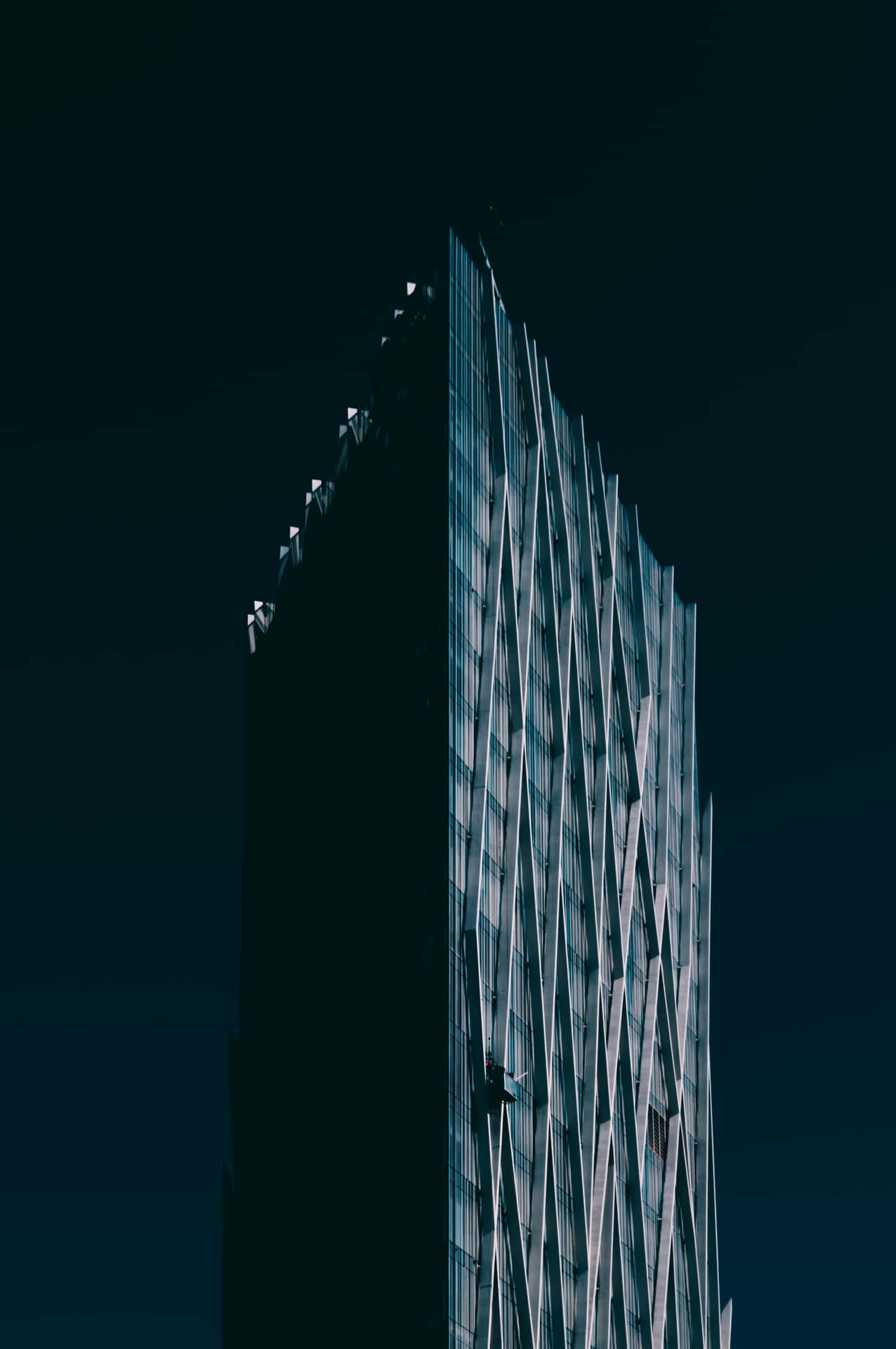 夜間亮燈的鋸齒狀玻璃外牆高層現代建築