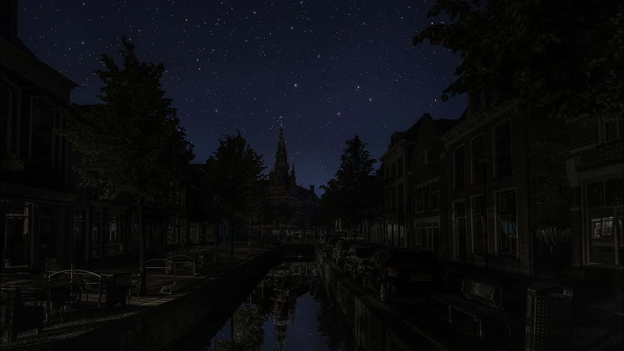 欣賞令人屏息的夜空 壁紙 — 星空在寧靜的運河中倒映，兩旁是黑暗的歷史建築和樹木。