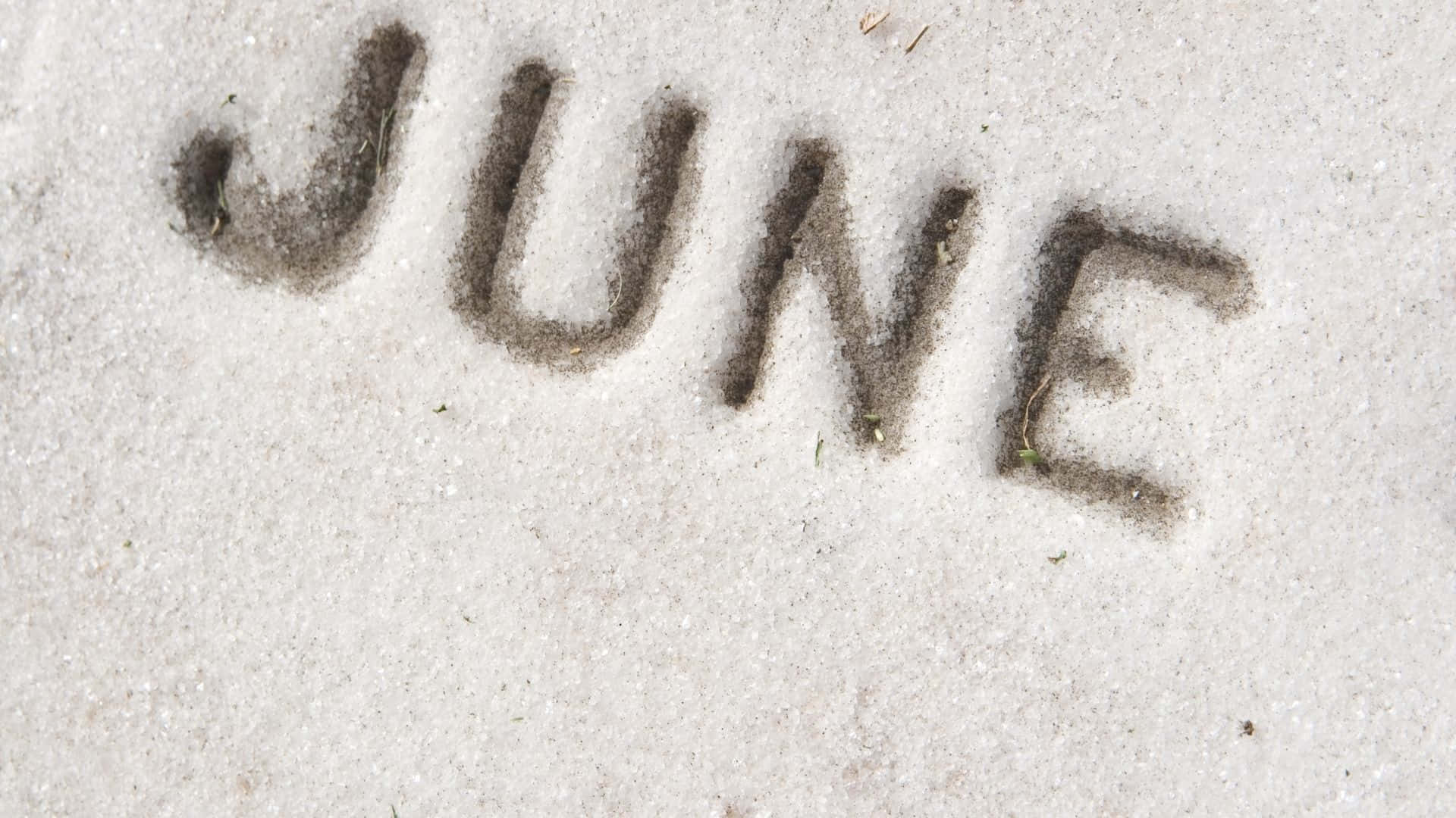 沙灘上嘅沙寫住「JUNE」呢個字。