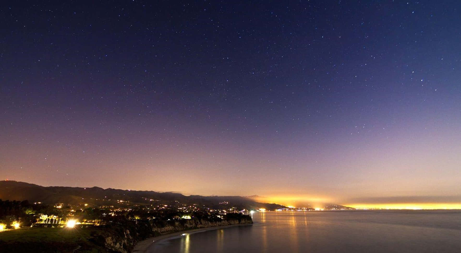 夜晚的沿海小鎮，星空下燈光映照在水面上。