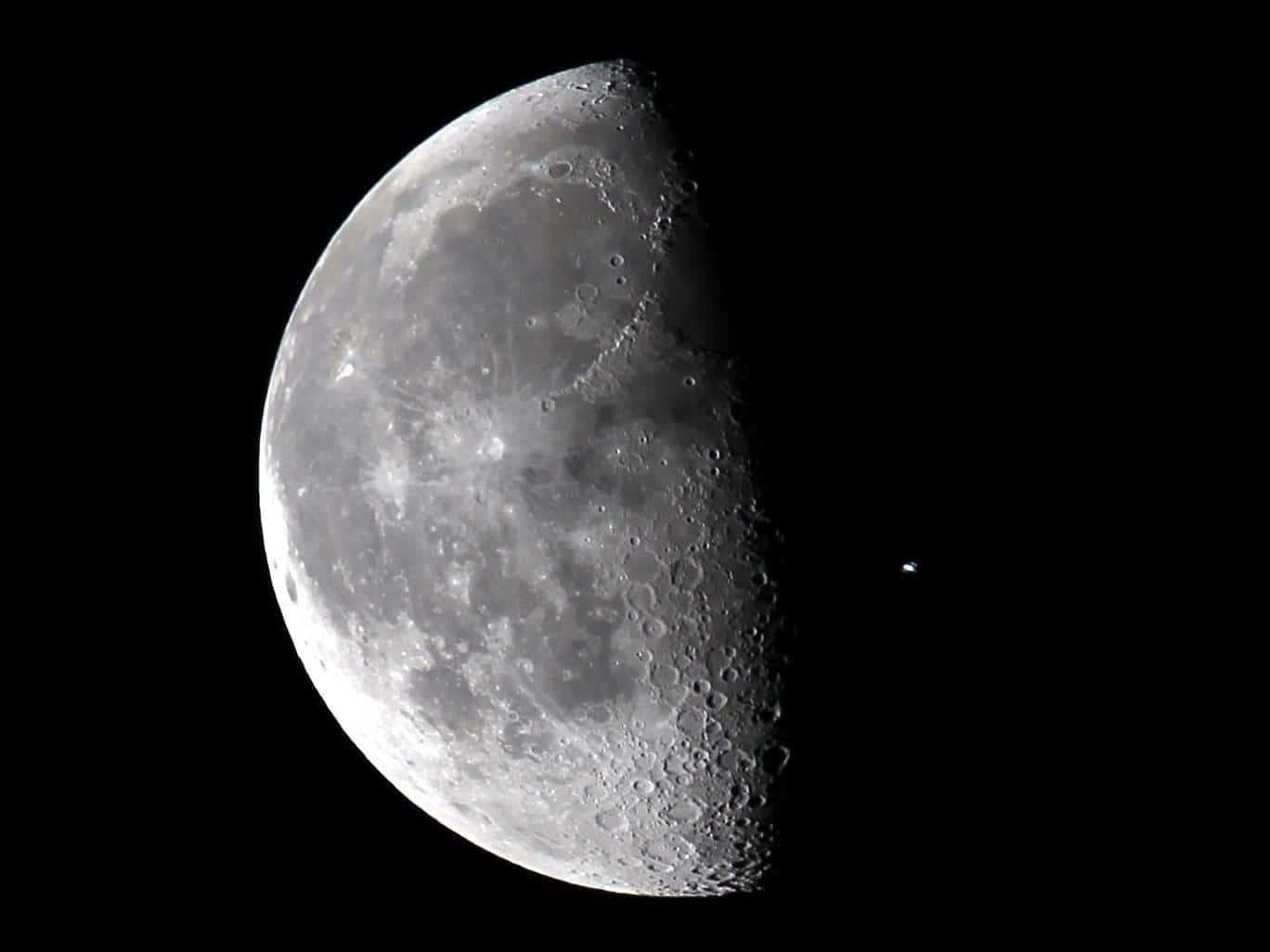 在黑暗的星空中，可見隕石坑的半個月亮。
