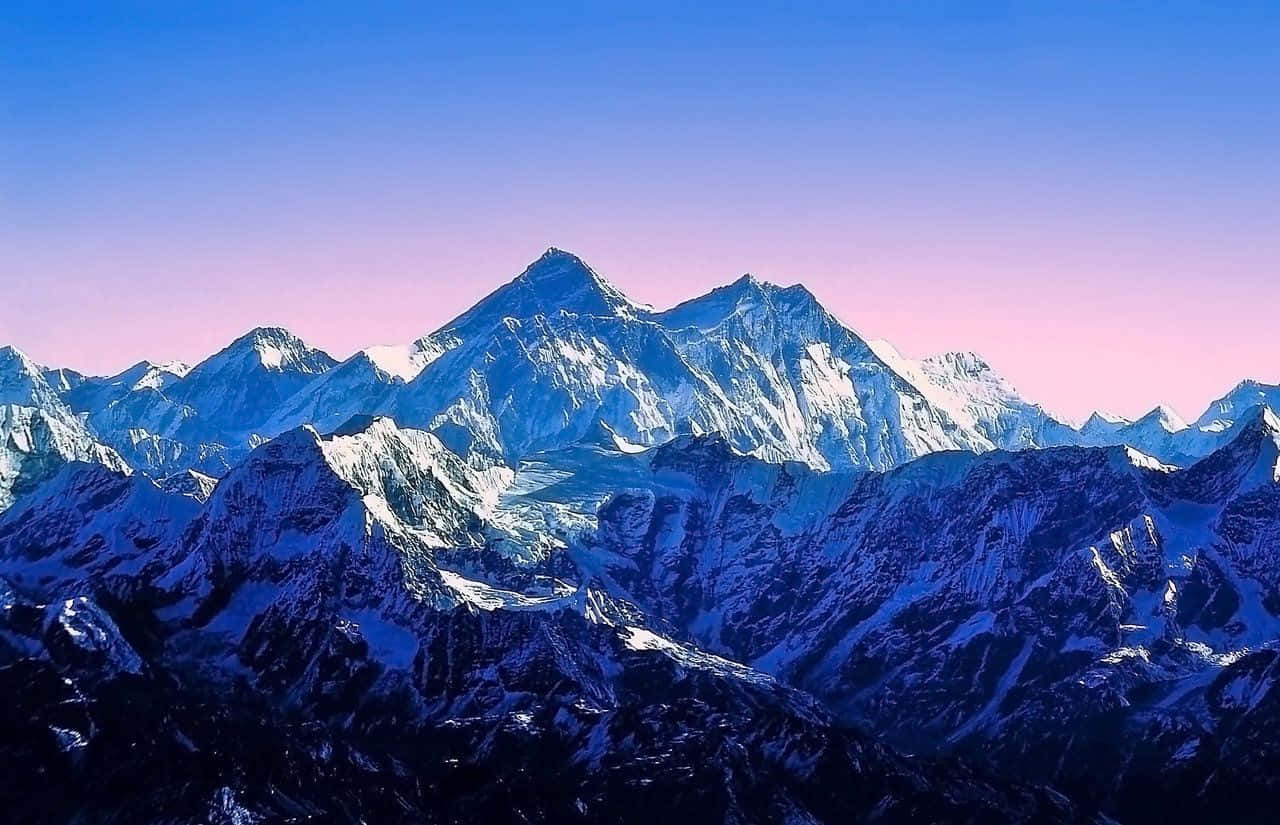 在粉紅色和藍色的黎明天空下，積雪的山脈