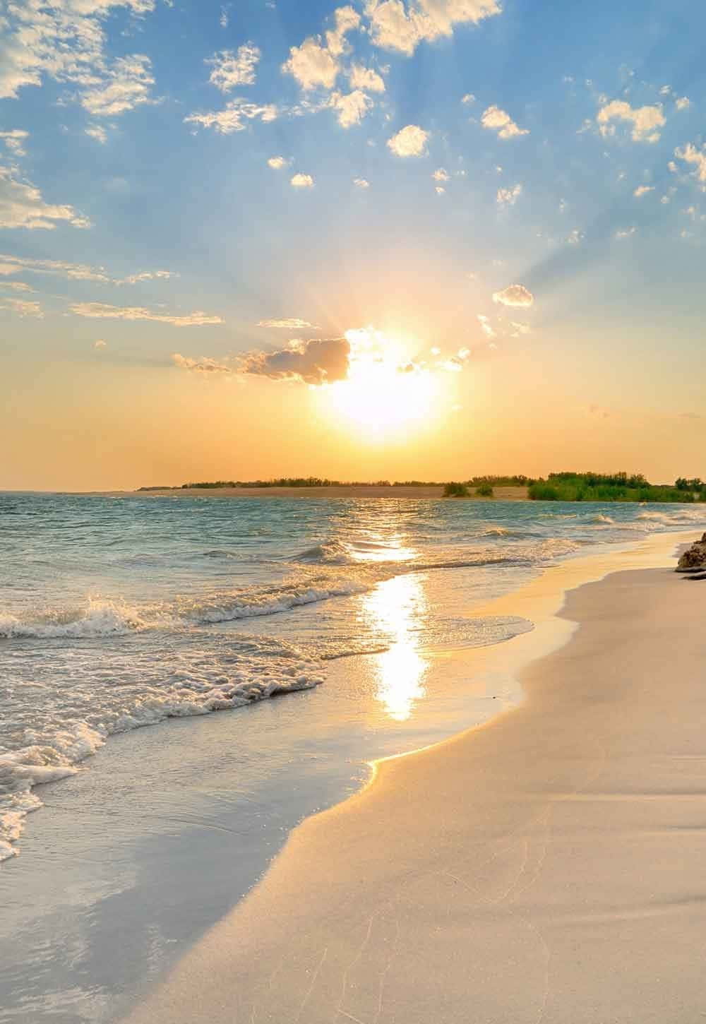 欣賞夏日海灘日的美景，感受這迷人的背景 壁紙 — 金色的夕陽穿過雲層，照耀在平靜的碧綠海面上，海浪沖刷著純淨的白色沙灘。