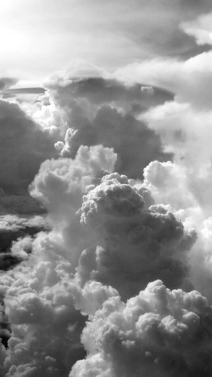 欣賞寧靜天空與蓬鬆雲朵 壁紙 — 戲劇性的單色雲朵在明亮的天空中盤旋，形成高聳且帶有紋理的形狀。