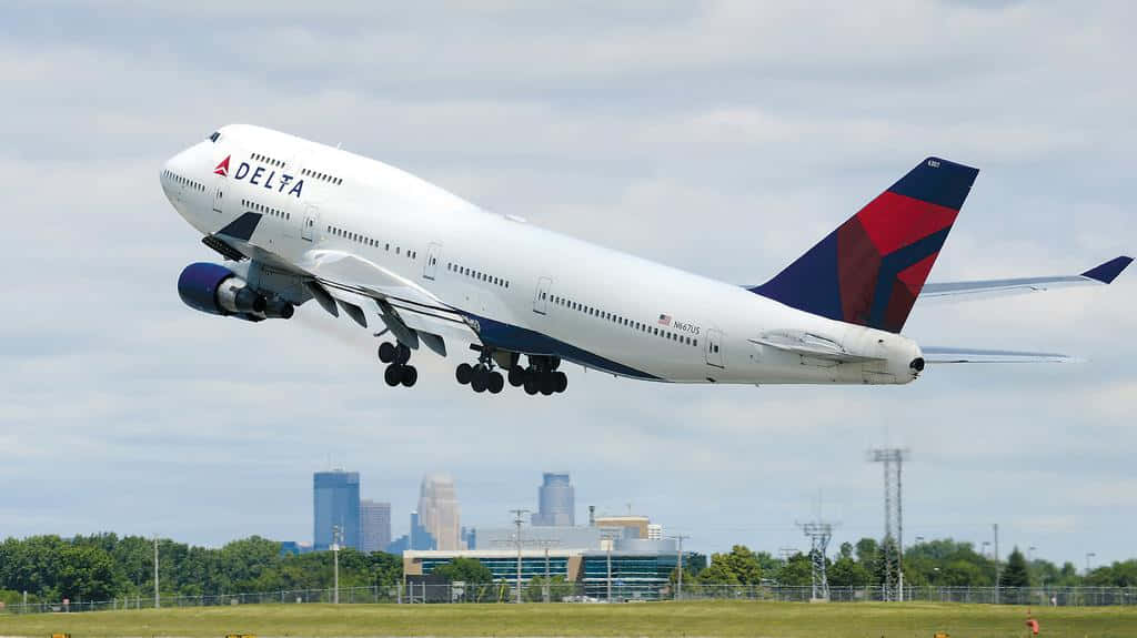 達美航空波音747從城市建築物附近的機場跑道起飛。