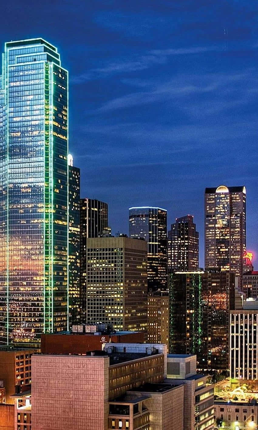 深藍色天空下，摩天大樓燈火輝煌的黃昏城市景觀。