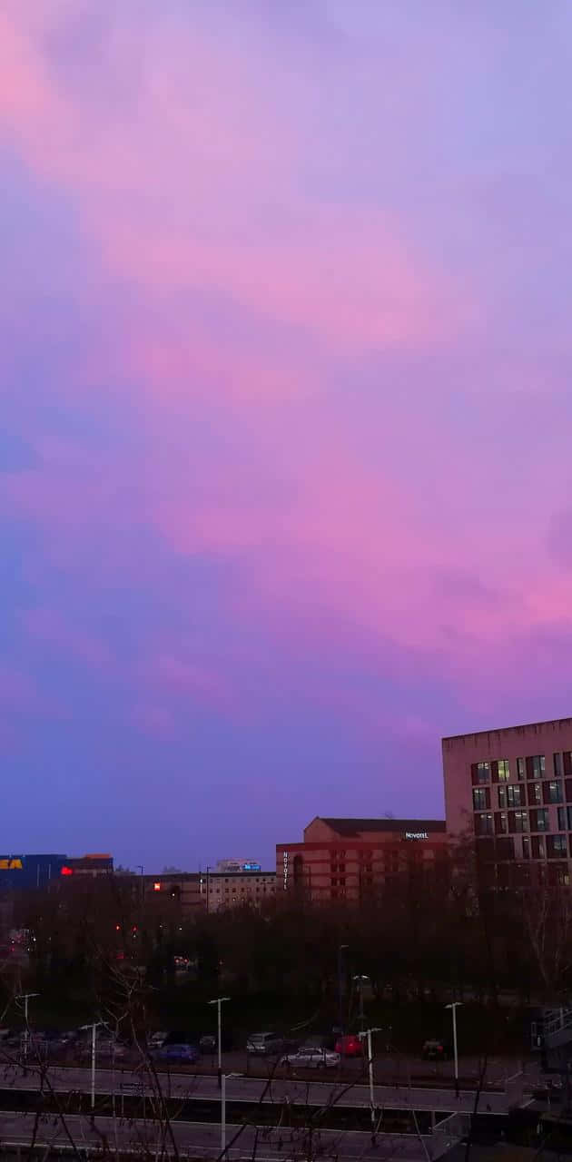 黃昏時分的城市天際線，粉紅色和紫色的天空與街燈。