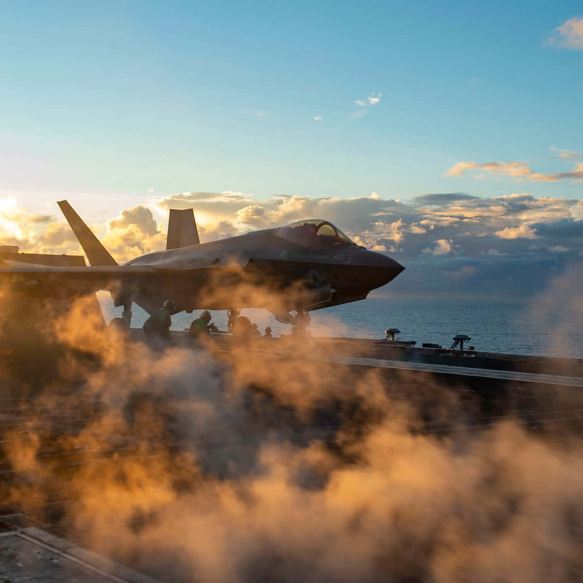 戰鬥機在航空母艦甲板上，伴隨煙霧和夕陽餘暉。