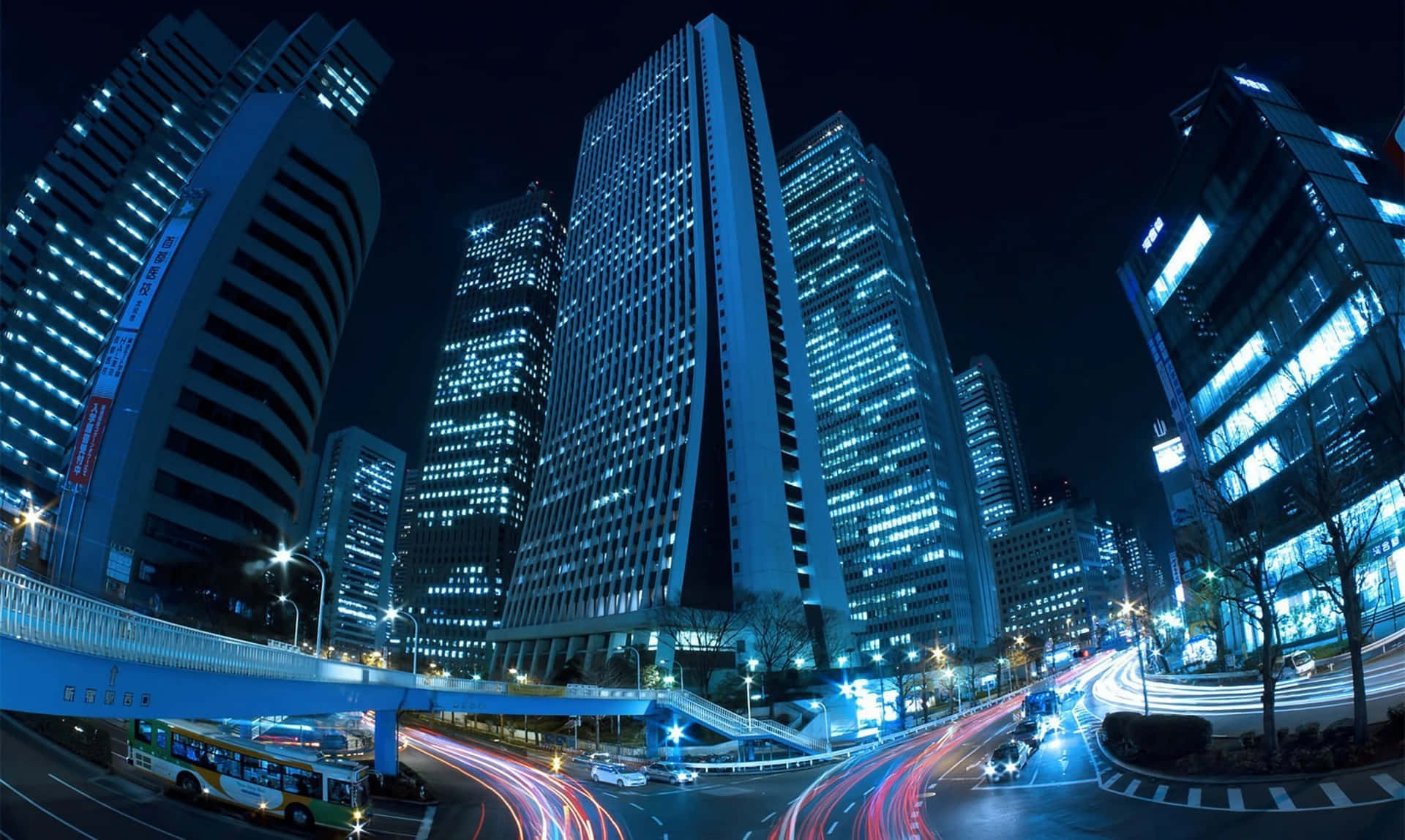 夜晚城市，高樓閃爍，移動車輛留下光軌。