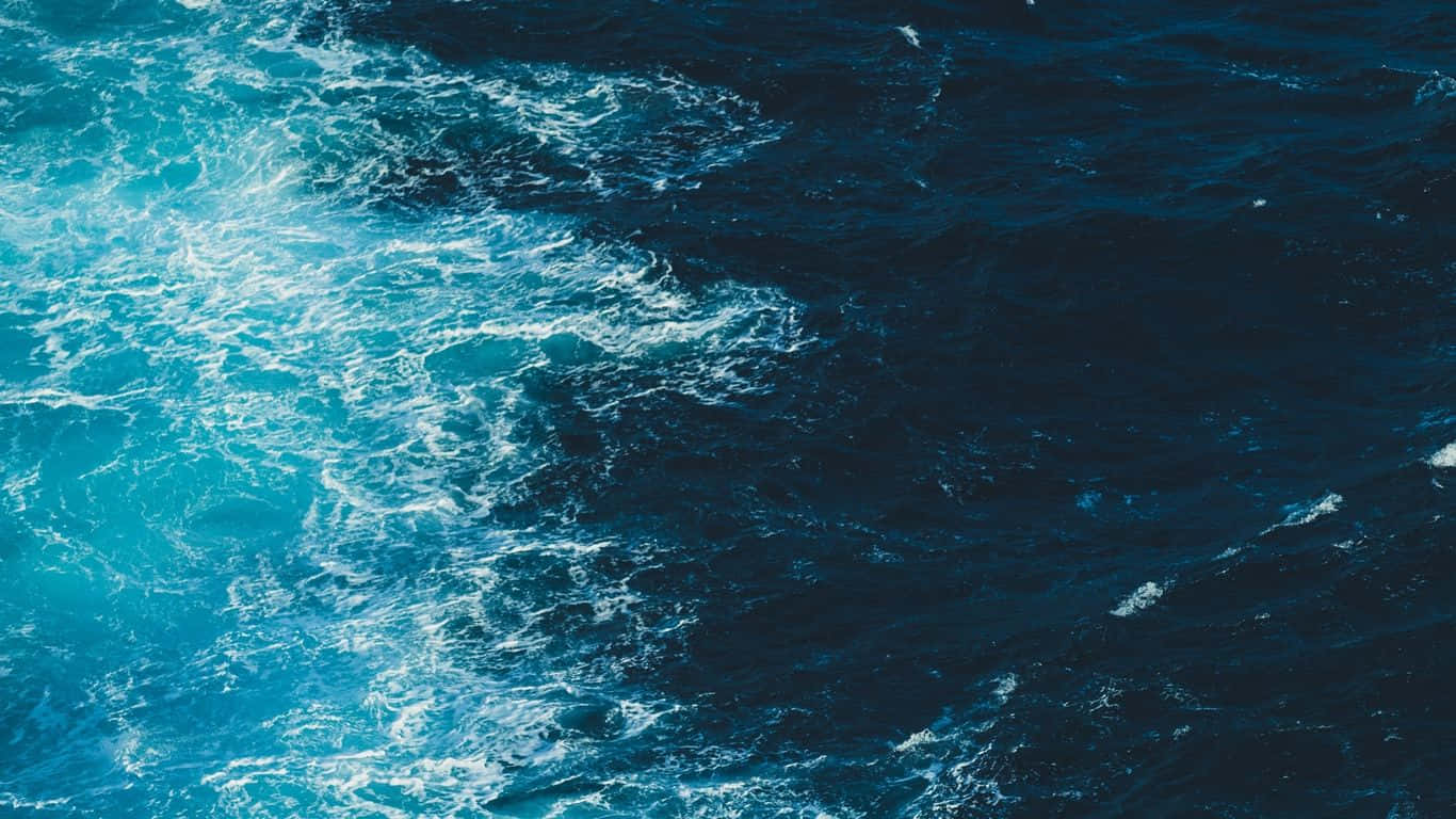 欣賞海洋之美 壁紙 — 從空中俯瞰湍急的海浪，帶有泡沫般的藍綠色痕跡劃過深藍色的海水。