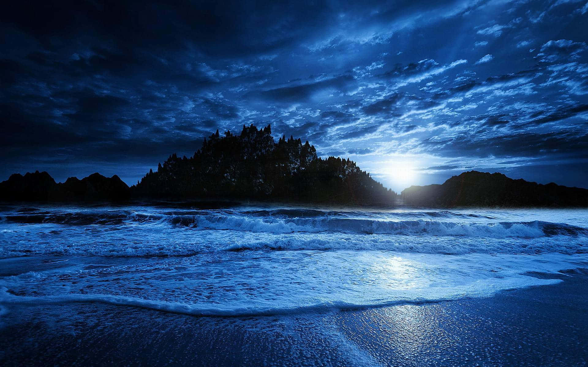 欣賞海灘夜間的美景 壁紙 — 月光穿過暴風雲層，照耀著波濤洶湧的海洋，拍打著黑暗的岩石海岸。