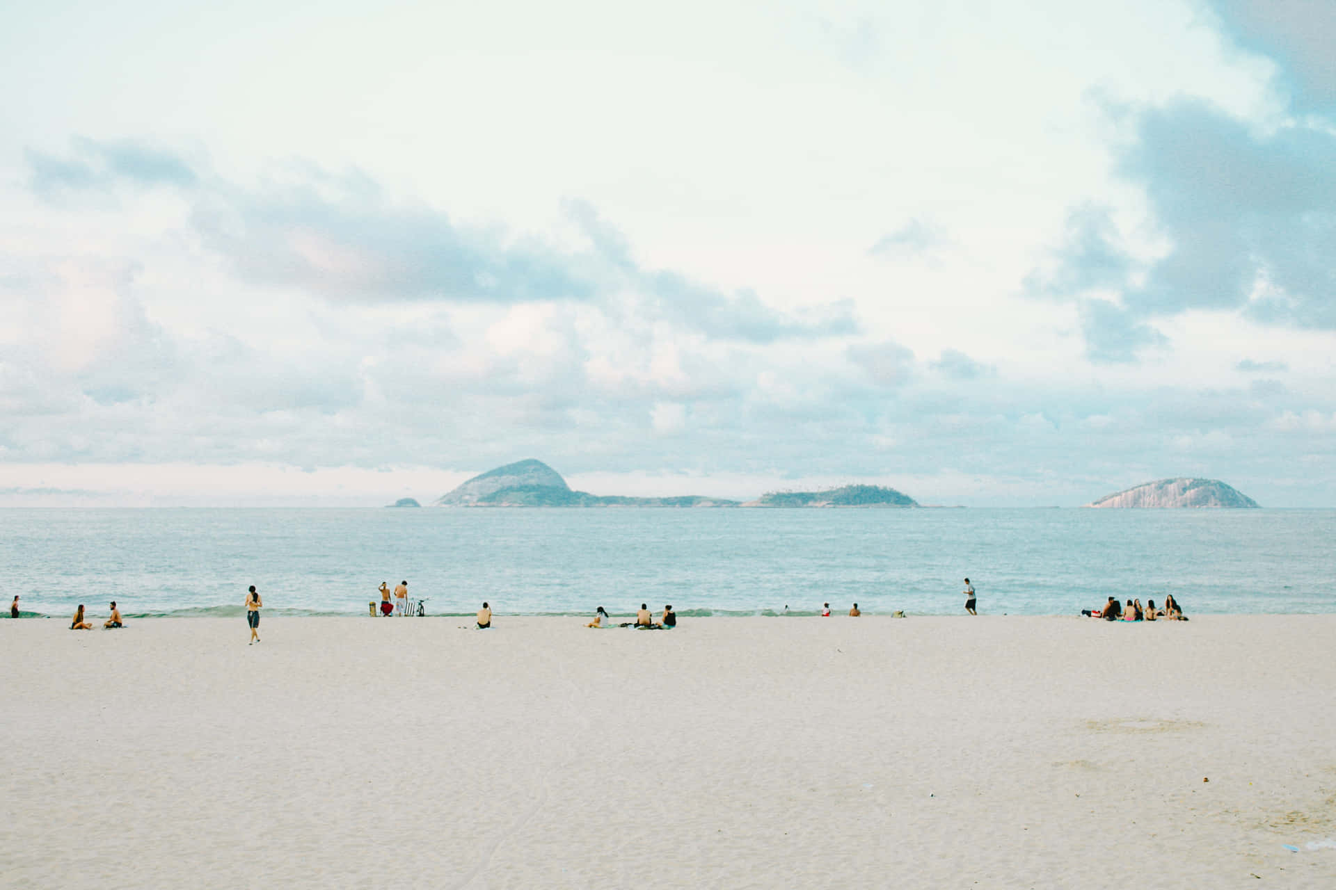 人們享受平靜的海灘日，遠處可見島嶼。