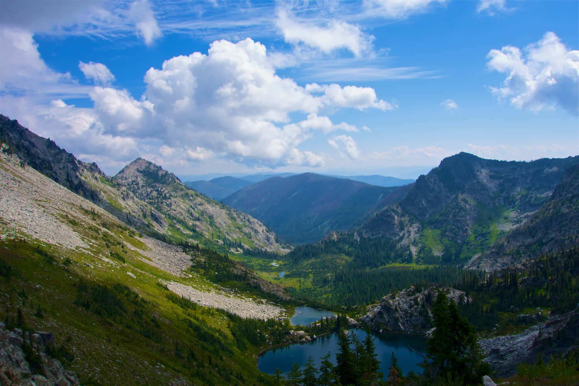 一個風景如畫的山谷，湖泊被森林和岩石山峰環繞，天空多雲。