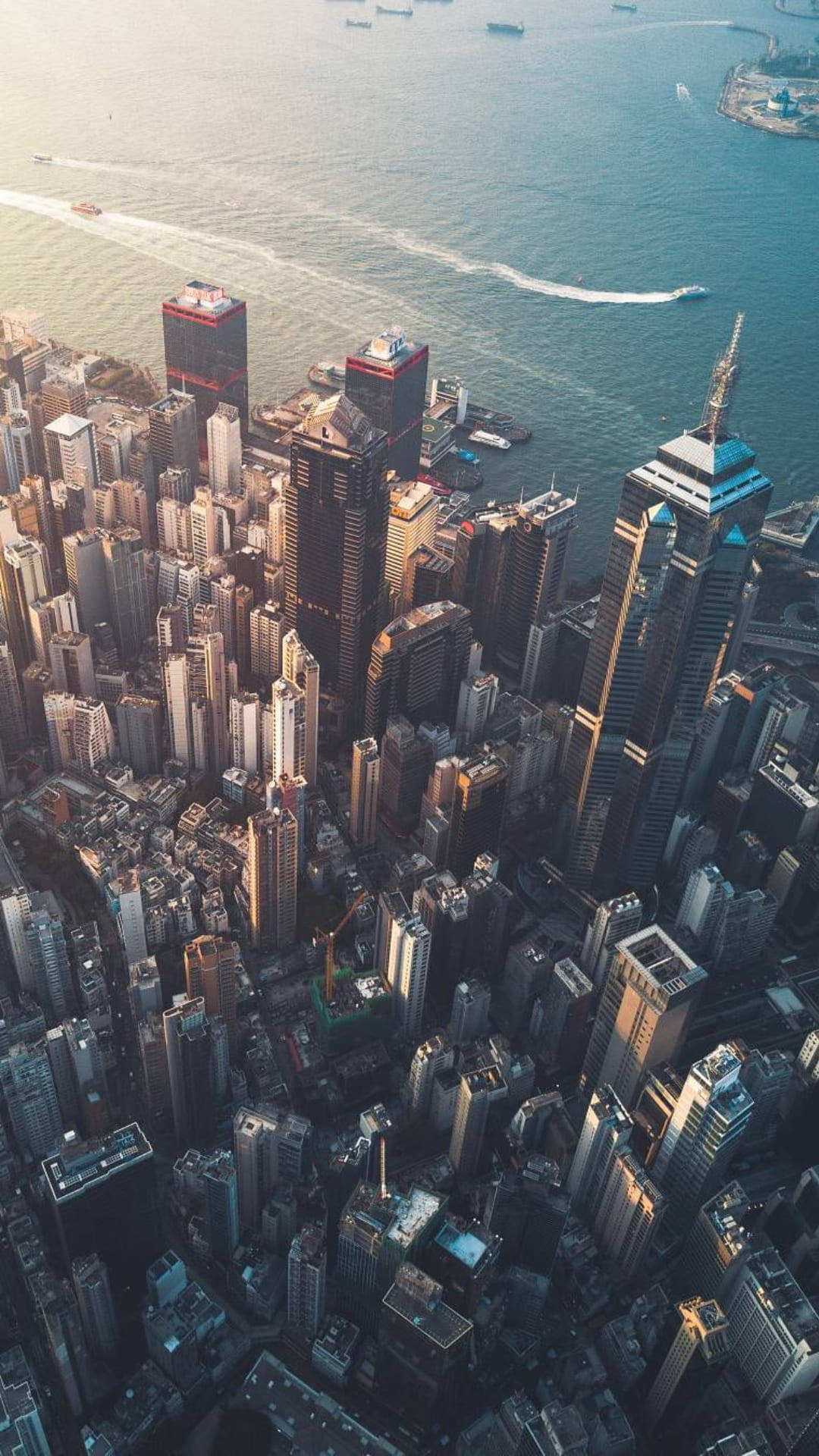 欣賞紐約市帝國大廈的日落美景 壁紙 — 黃金時段密集城市天際線的鳥瞰圖，摩天大樓在繁忙的港口旁反射溫暖的光芒。