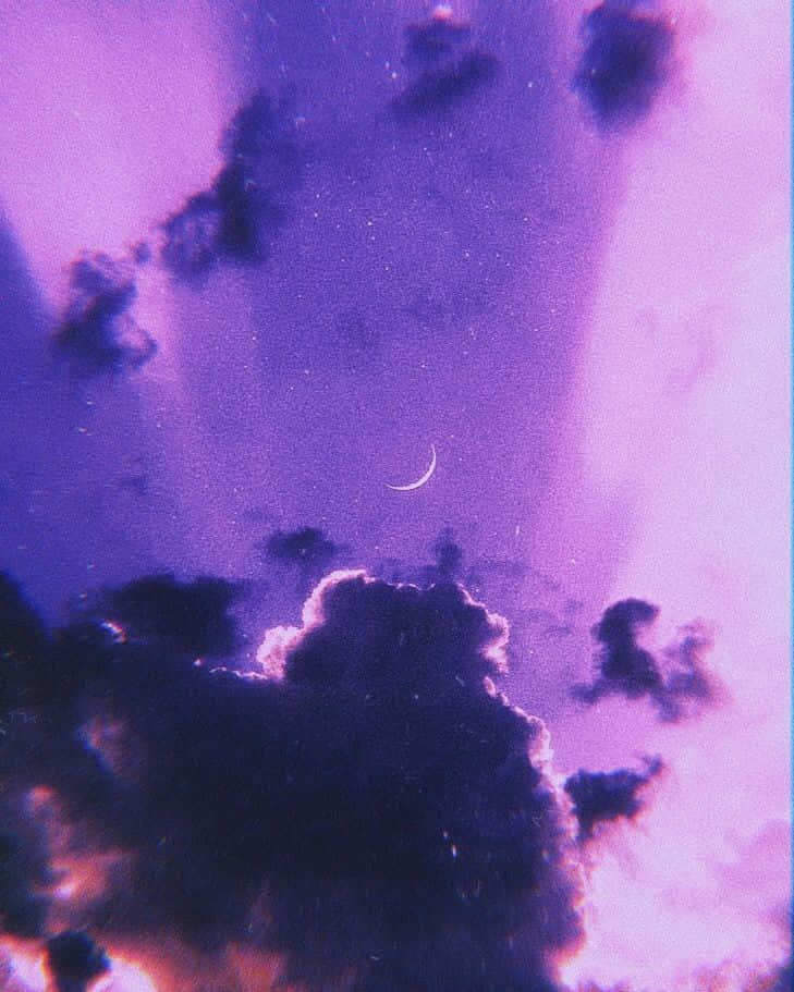 欣賞紫調風景的絕美魅力 壁紙 — 夢幻的紫色天空，帶有新月和暗雲，邊緣閃爍著粉紅色和橙色。