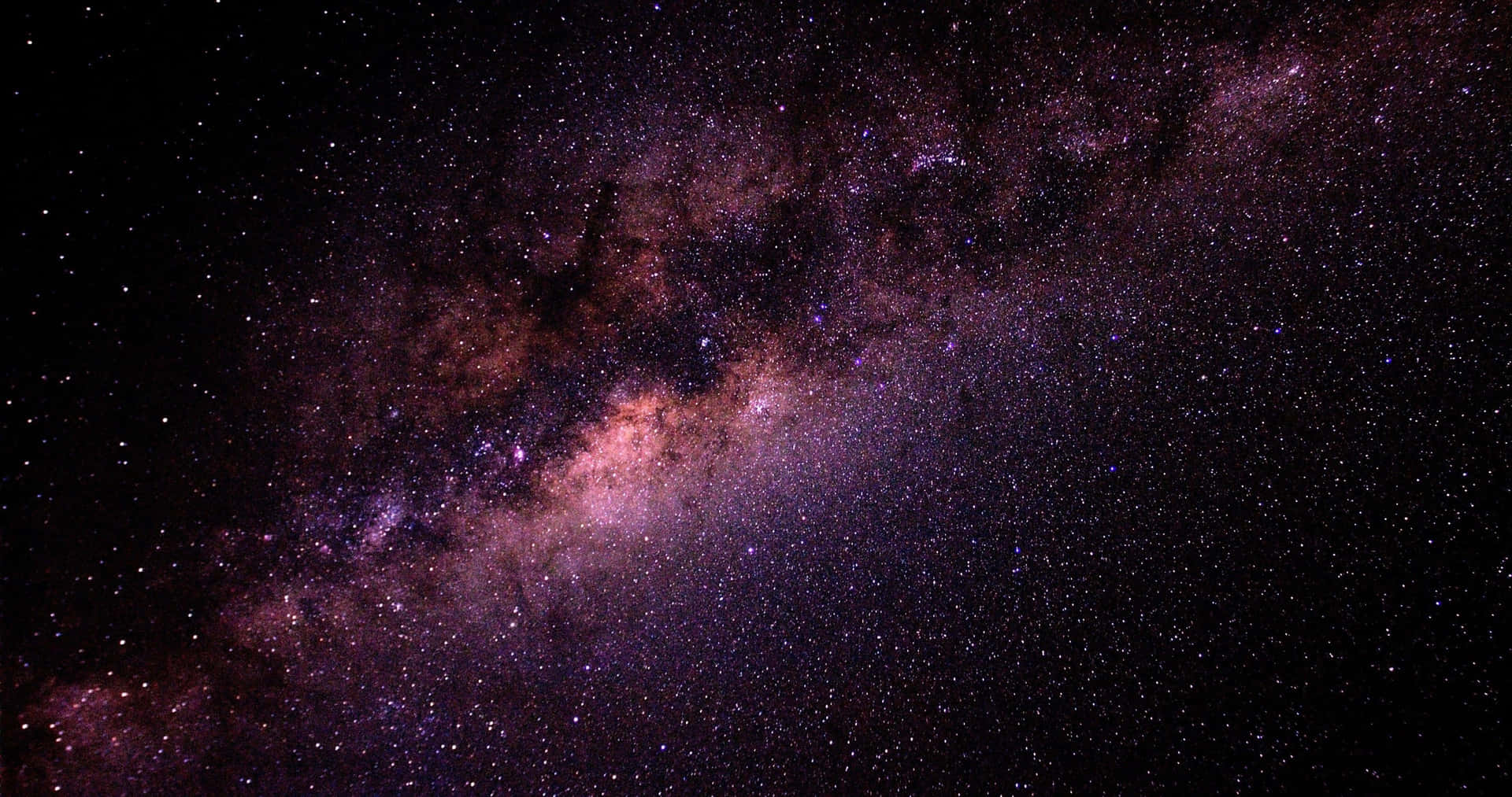 鮮豔的紫色和粉紅色銀河系在黑暗的星空中延伸。