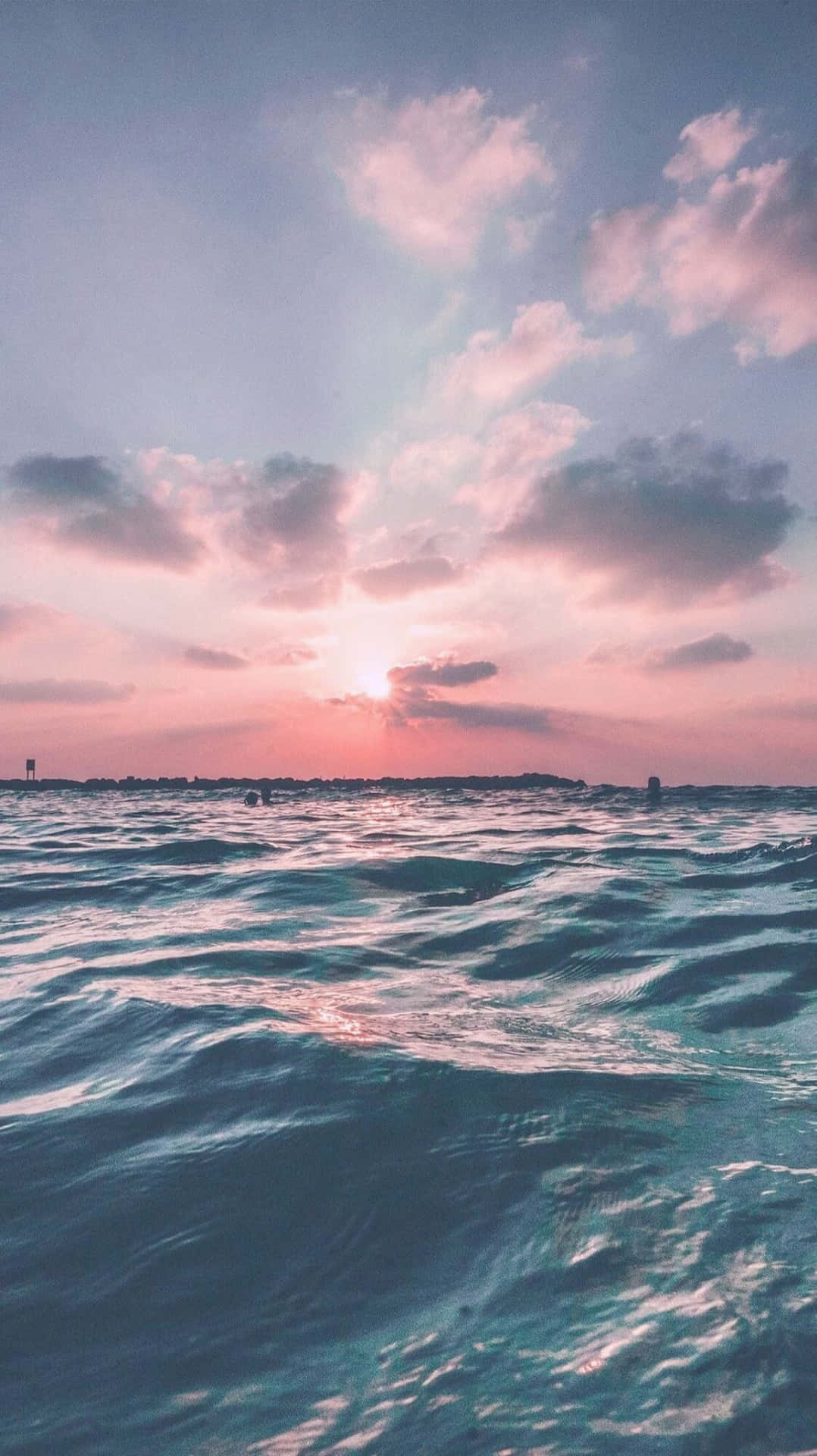 夕陽下的海浪與粉紅和藍色的天空