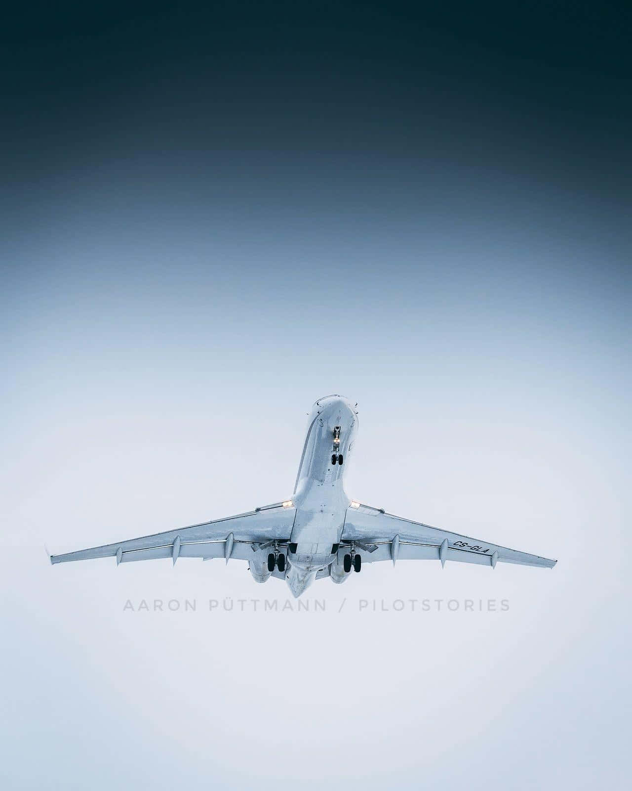 欣賞飛機飛越美麗藍天 壁紙 — 一架流線型白色飛機向上翱翔，背景是從淺藍色漸變到深藍綠色的天空。