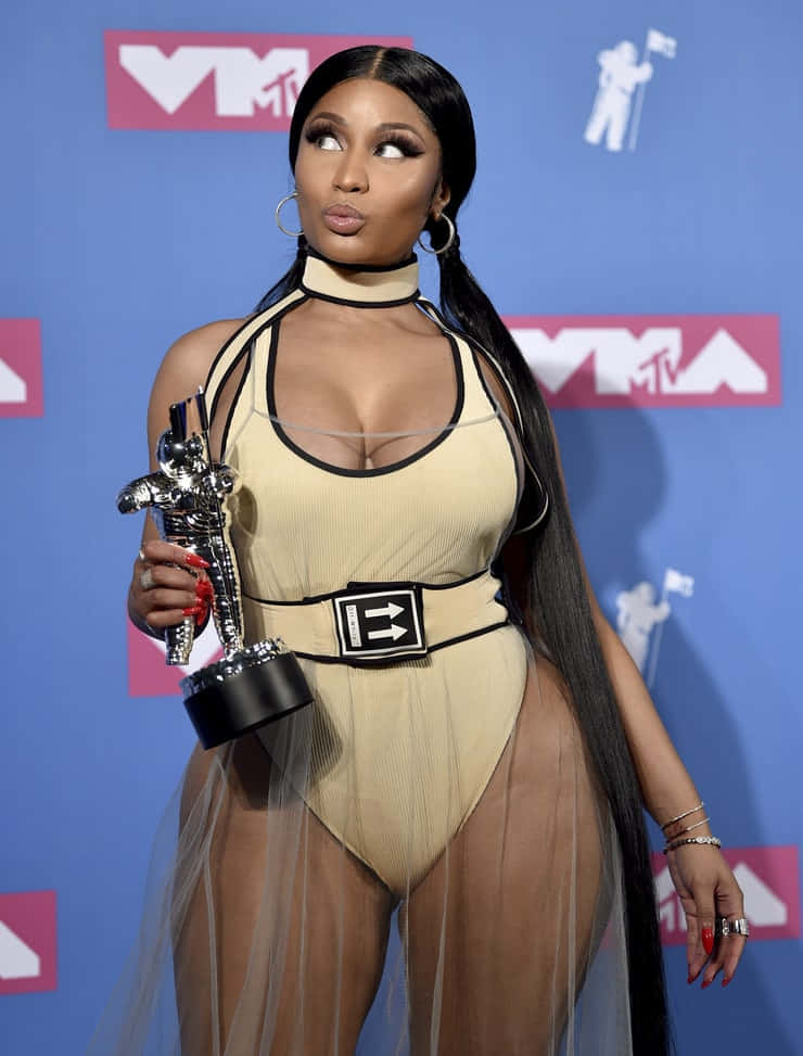 身穿米色服裝的女性在活動中手持MTV獎項。