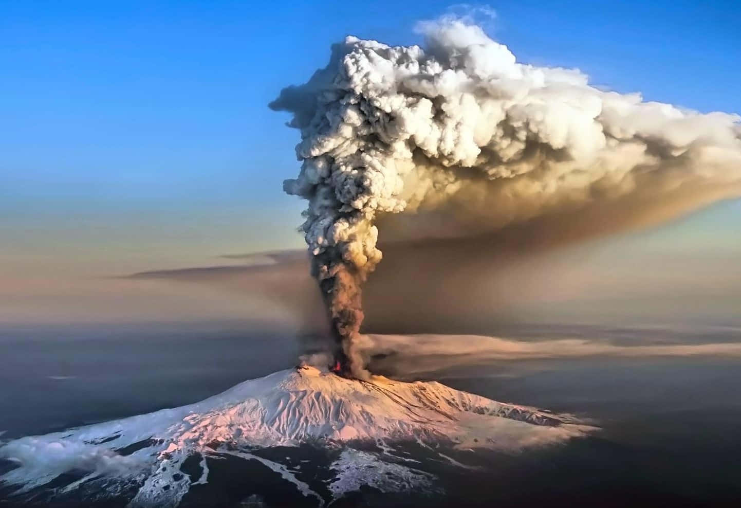歐洲最大埃特納火山 壁紙 — 一座積雪覆蓋的火山劇烈噴發，在日出時將巨大的火山灰雲送入清澈的藍天。