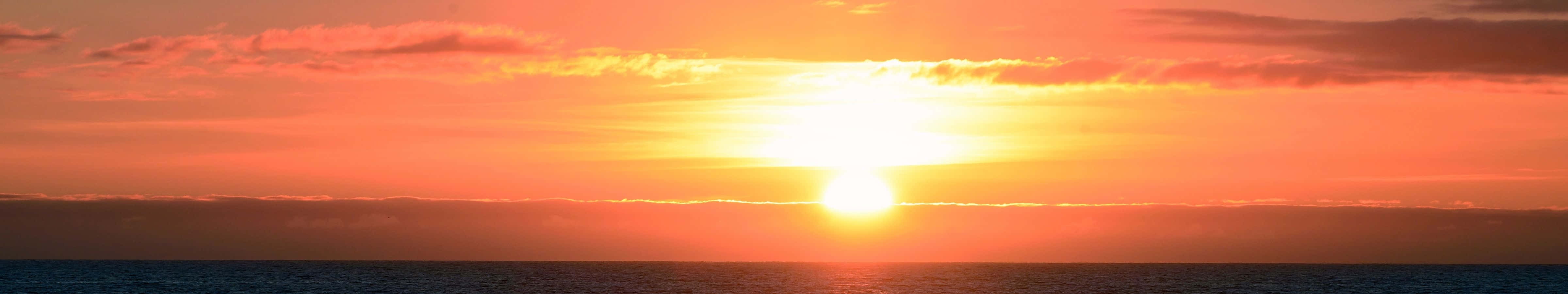 夕陽映照海洋，天空呈現鮮豔的橙色和金色