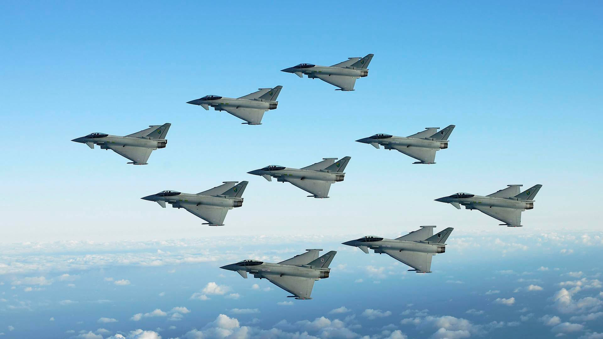 歐洲颱風戰鬥機編隊 壁紙 — 八架戰鬥機在晴朗藍天下，於蓬鬆白雲上方緊密編隊飛行。