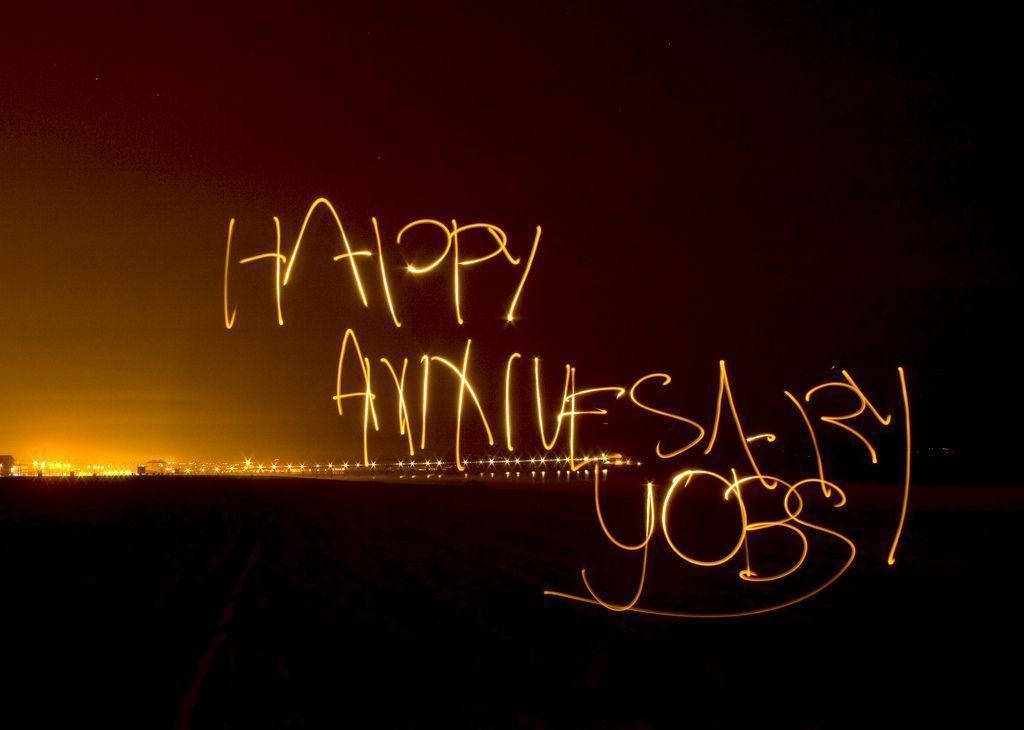 在夜間城市景觀上以發光光跡寫成的 happy anniversary。