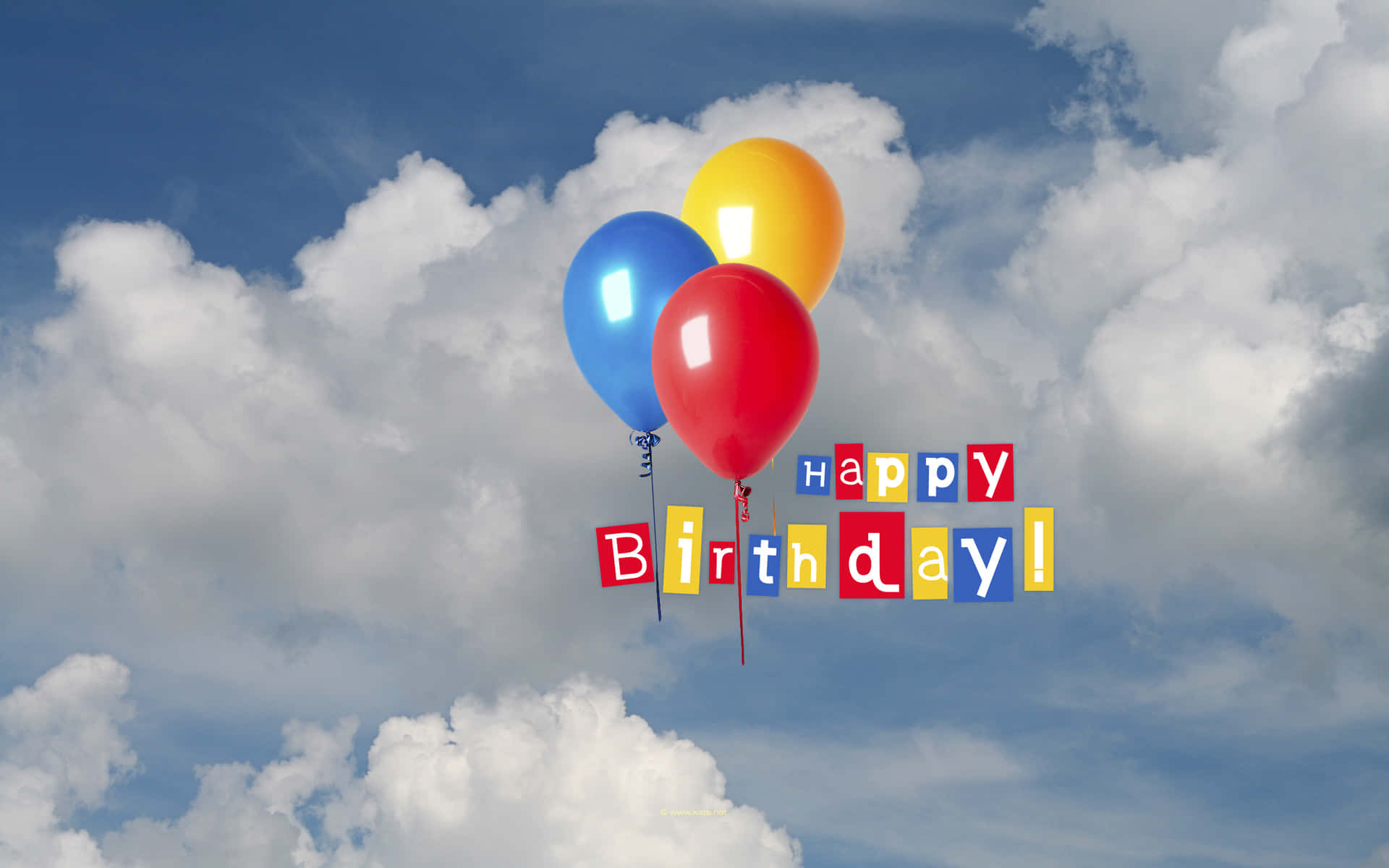 三個帶有生日快樂訊息的氣球在陰天飄浮。