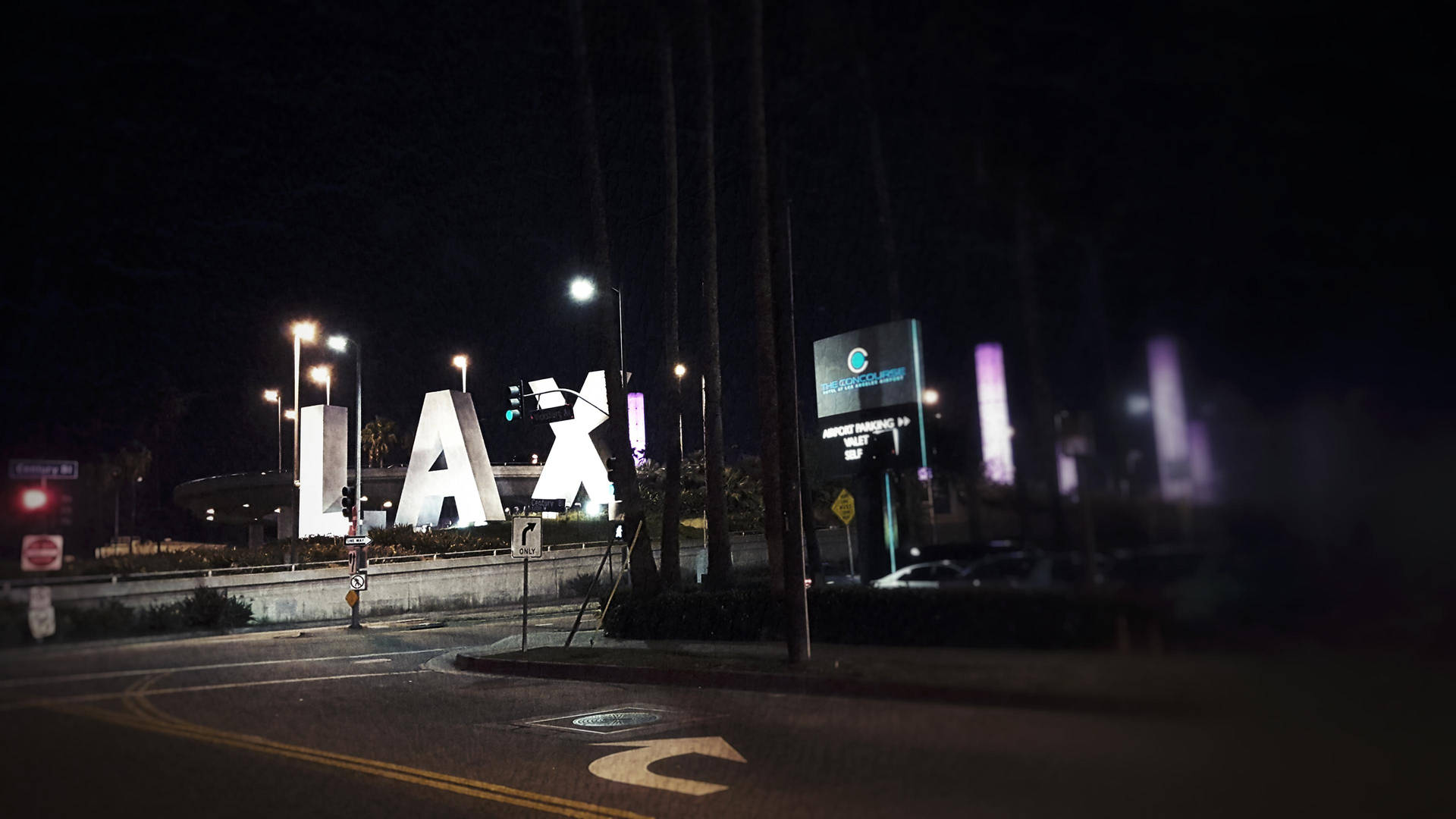 LAX機場標誌在夜間亮起，前景有街燈和汽車。