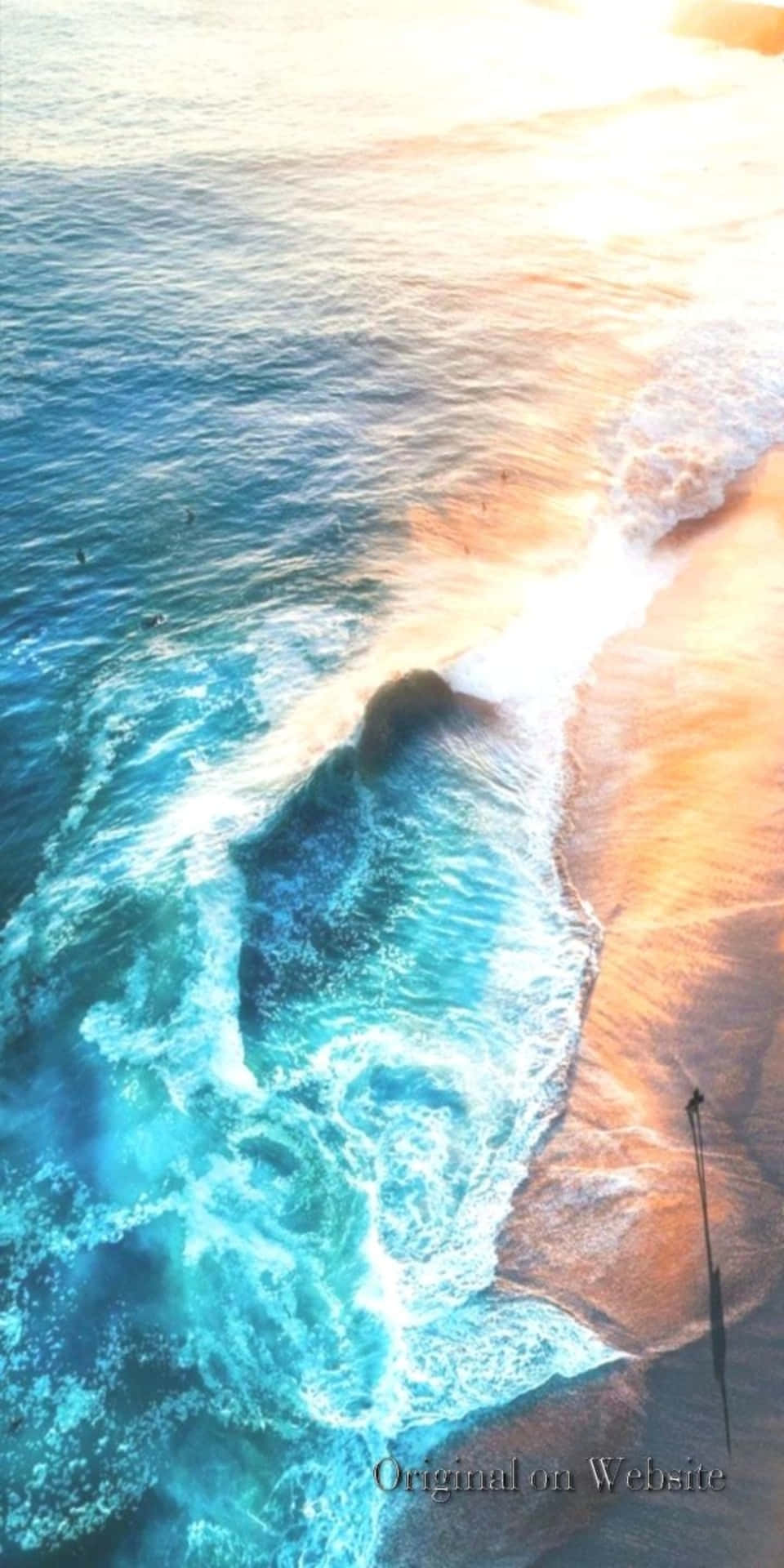 日落時分，海浪與金色沙灘相遇，衝浪者出現的鳥瞰圖。