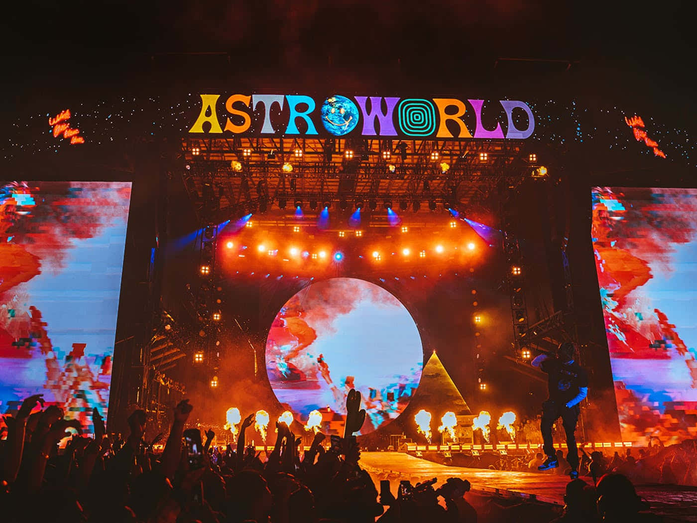 在發光的舞台下，帶有 'ASTROWORLD' 標誌的彩色夜間演唱會人群。