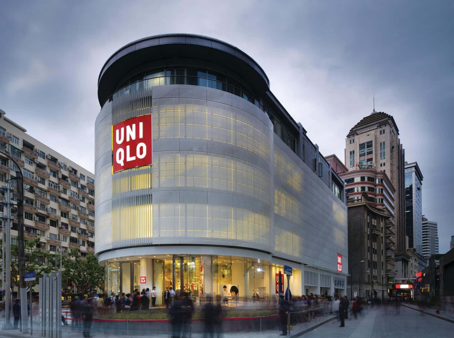 一間彎曲的Uniqlo商店，帶有發光的窗戶，位於繁忙的城市街道上。
