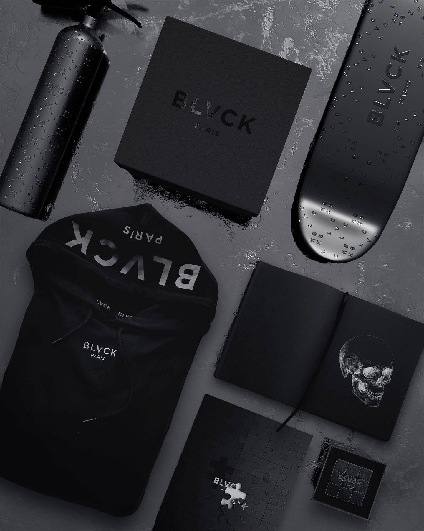 BLVCK PARIS 品牌服裝及配件在潮濕表面上的單色平鋪展示。