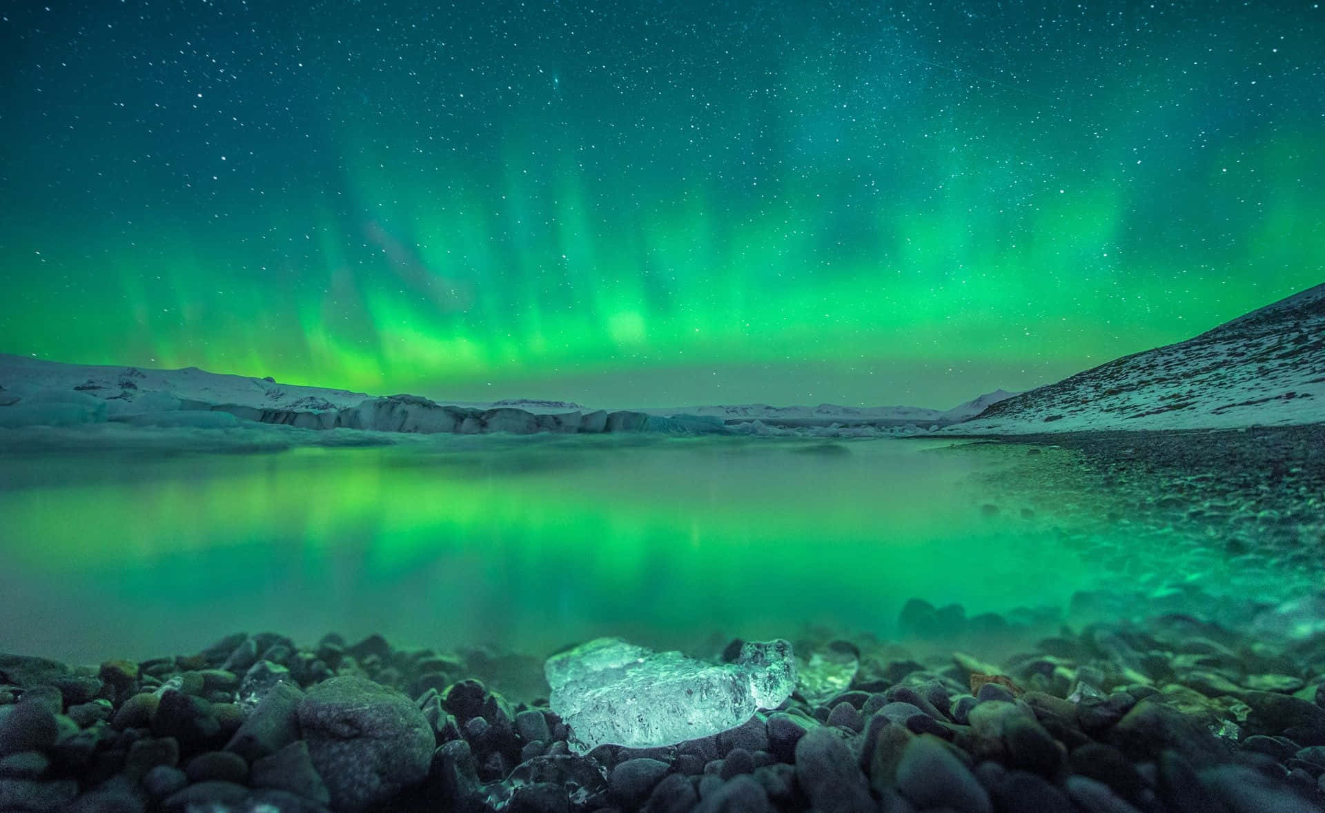 綠色北極光照亮星空下的結冰湖面。
