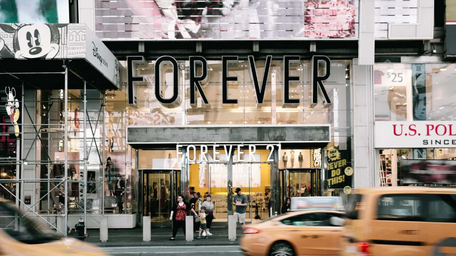 歡迎進入Forever 21時尚世界！ 壁紙 — 紐約市繁華的街景，有Forever 21商店、行人及移動模糊的黃色出租車。