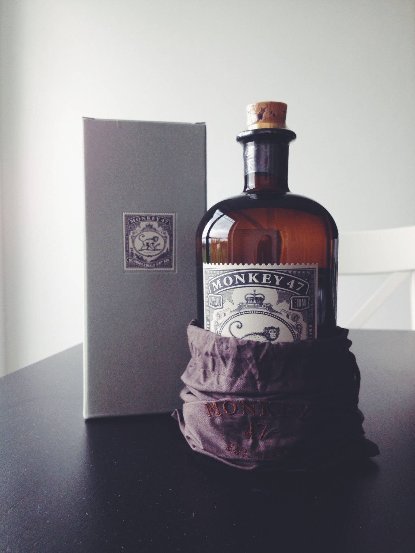 Monkey 47氈酒瓶在天鵝絨套中與盒子在深色桌上