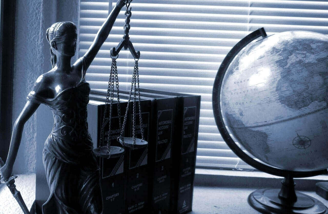正義女神雕像旁邊有法律書籍和一個地球儀在窗台上。
