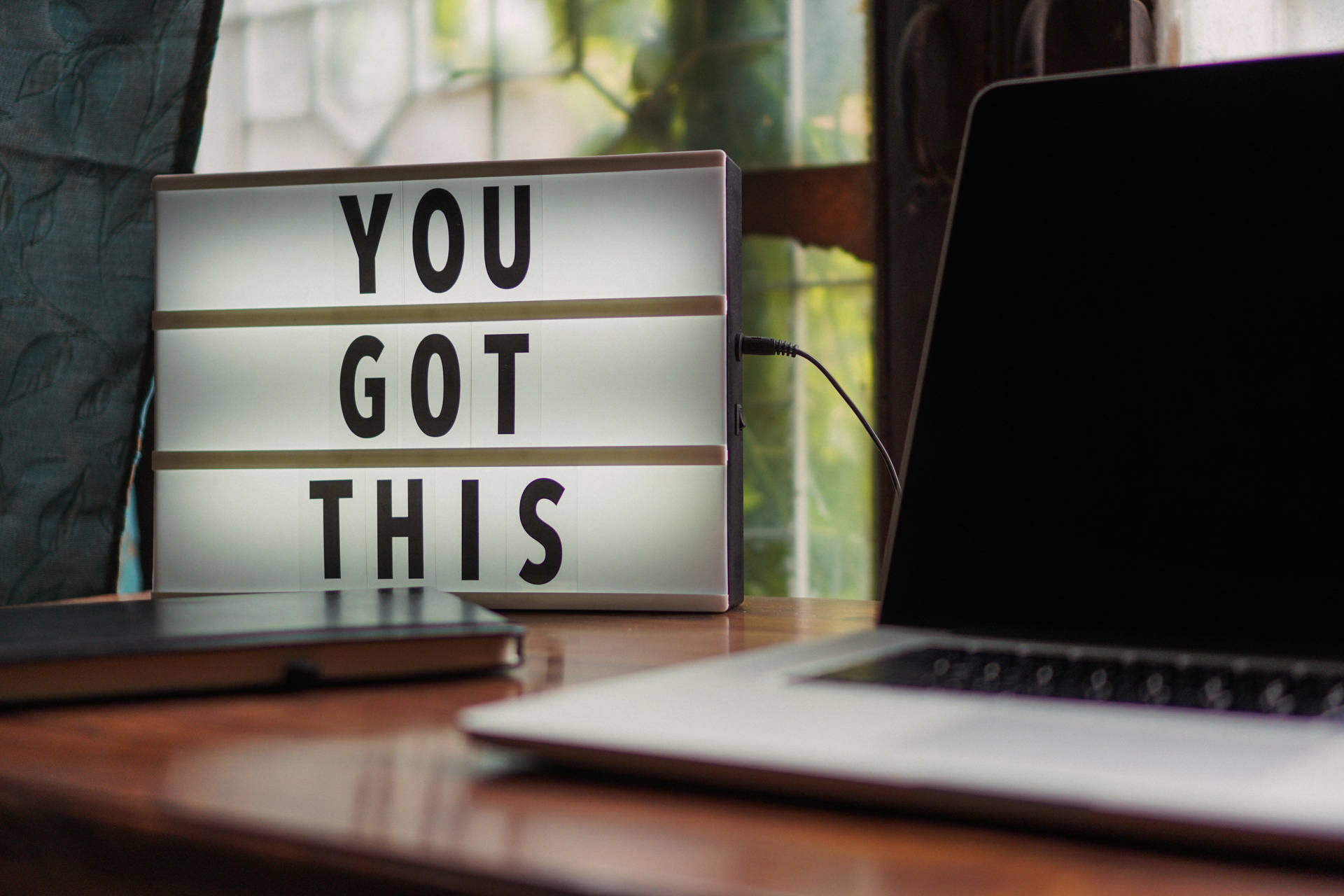 一個勵志燈箱，上面寫著「YOU GOT THIS」，放在木桌上，旁邊有一部手提電腦。