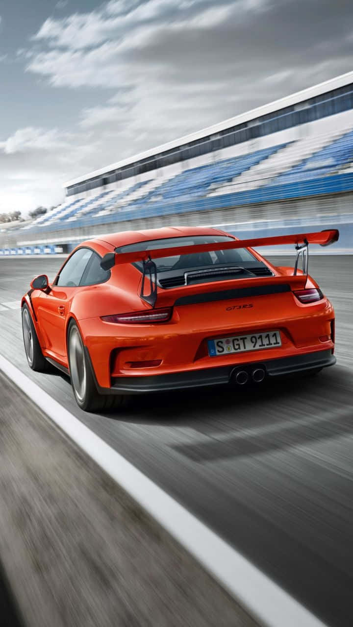 橙色保時捷911 GT3 RS在賽道上比賽，背景有模糊的看台。