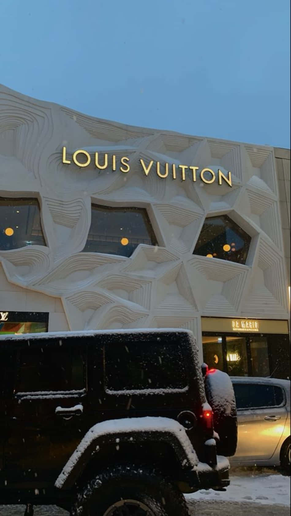 黑色吉普車被雪覆蓋，停在路易威登店外，在黃昏時分。