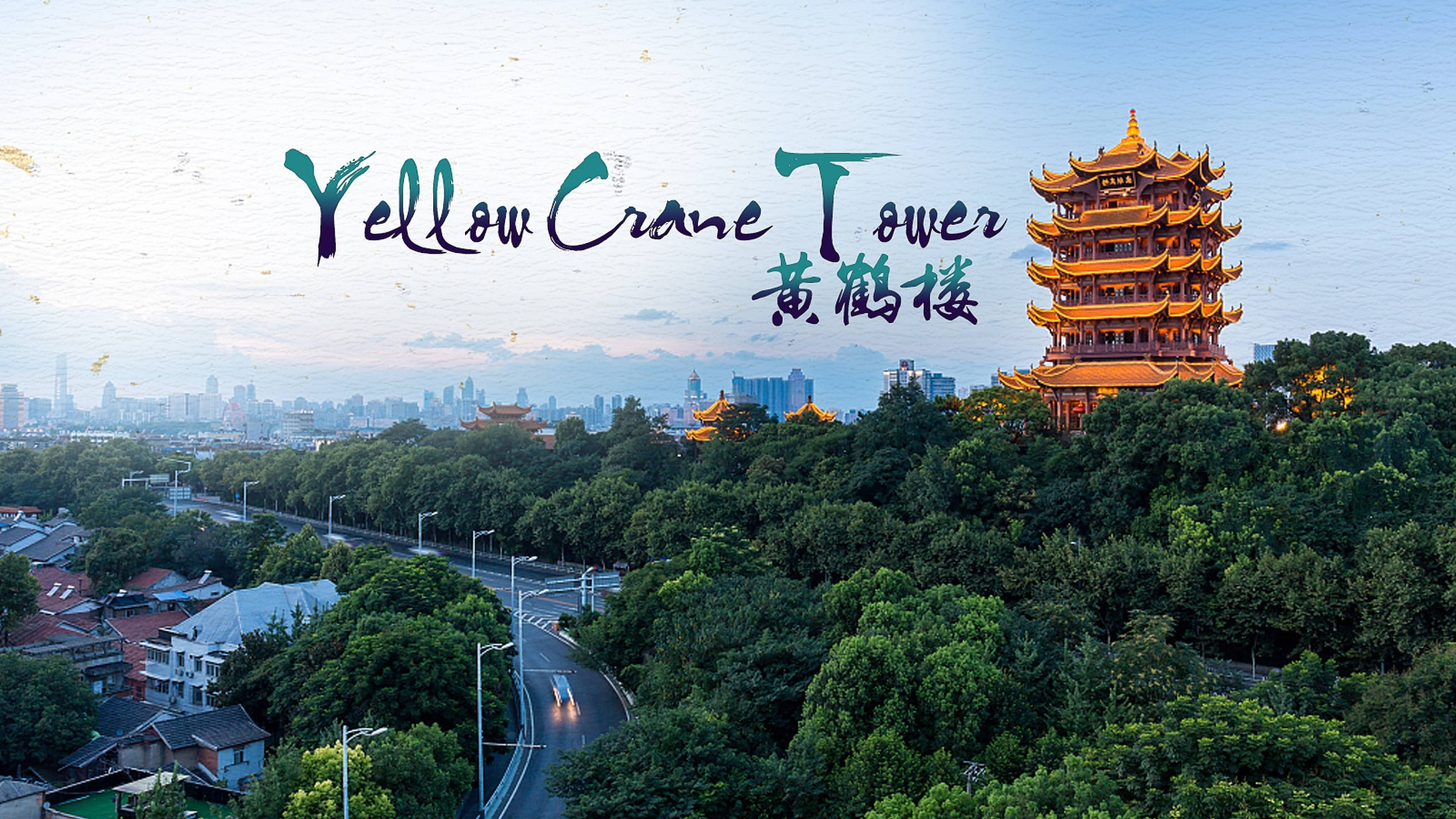 武漢黃鶴樓 壁紙 — 金黃色的黃鶴樓聳立在茂密的綠樹之上，暮色中隱約可見現代城市的天際線。