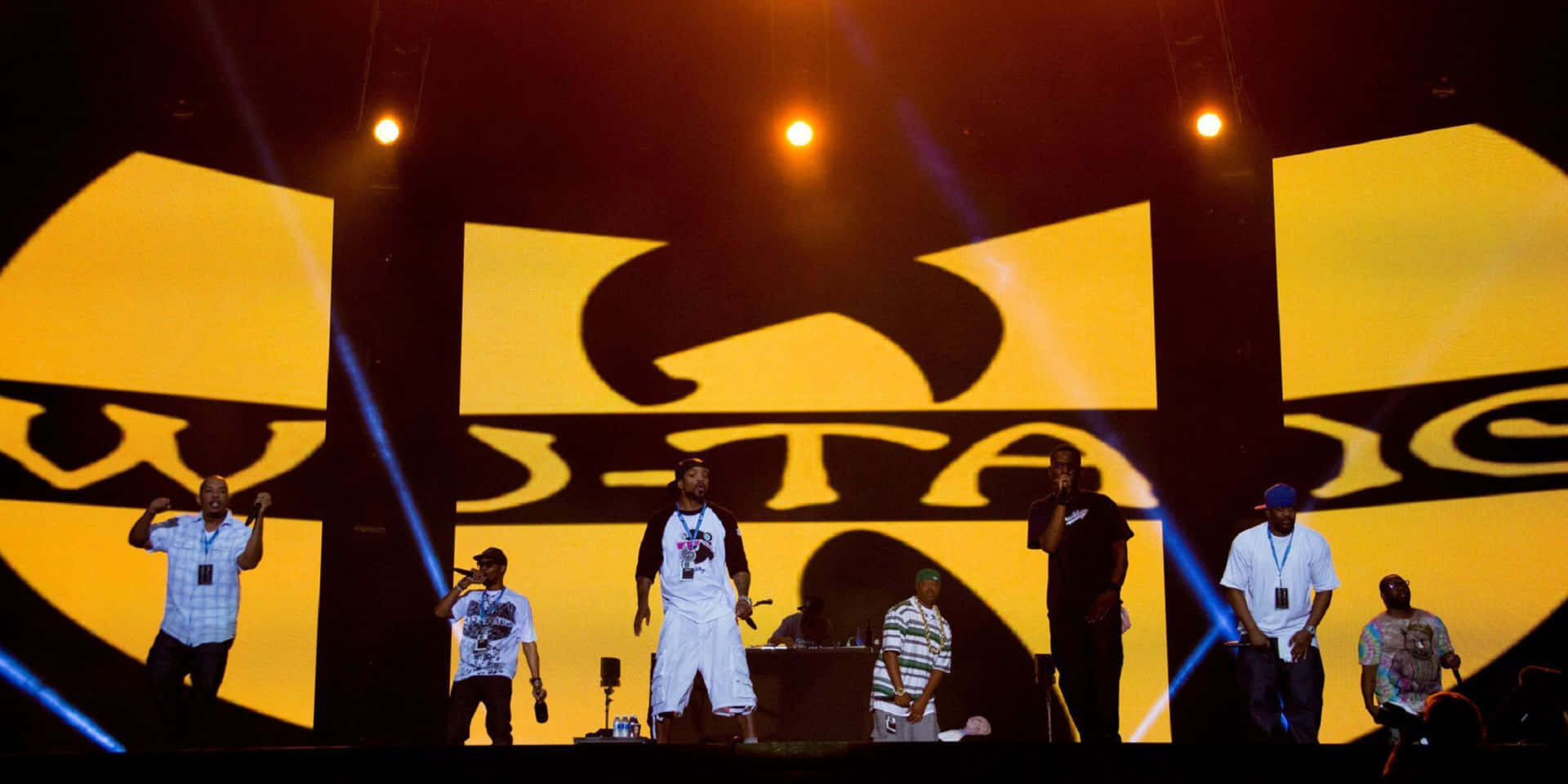 Wu-Tang Clan表演者在音樂會上於明亮燈光下在舞台上表演。