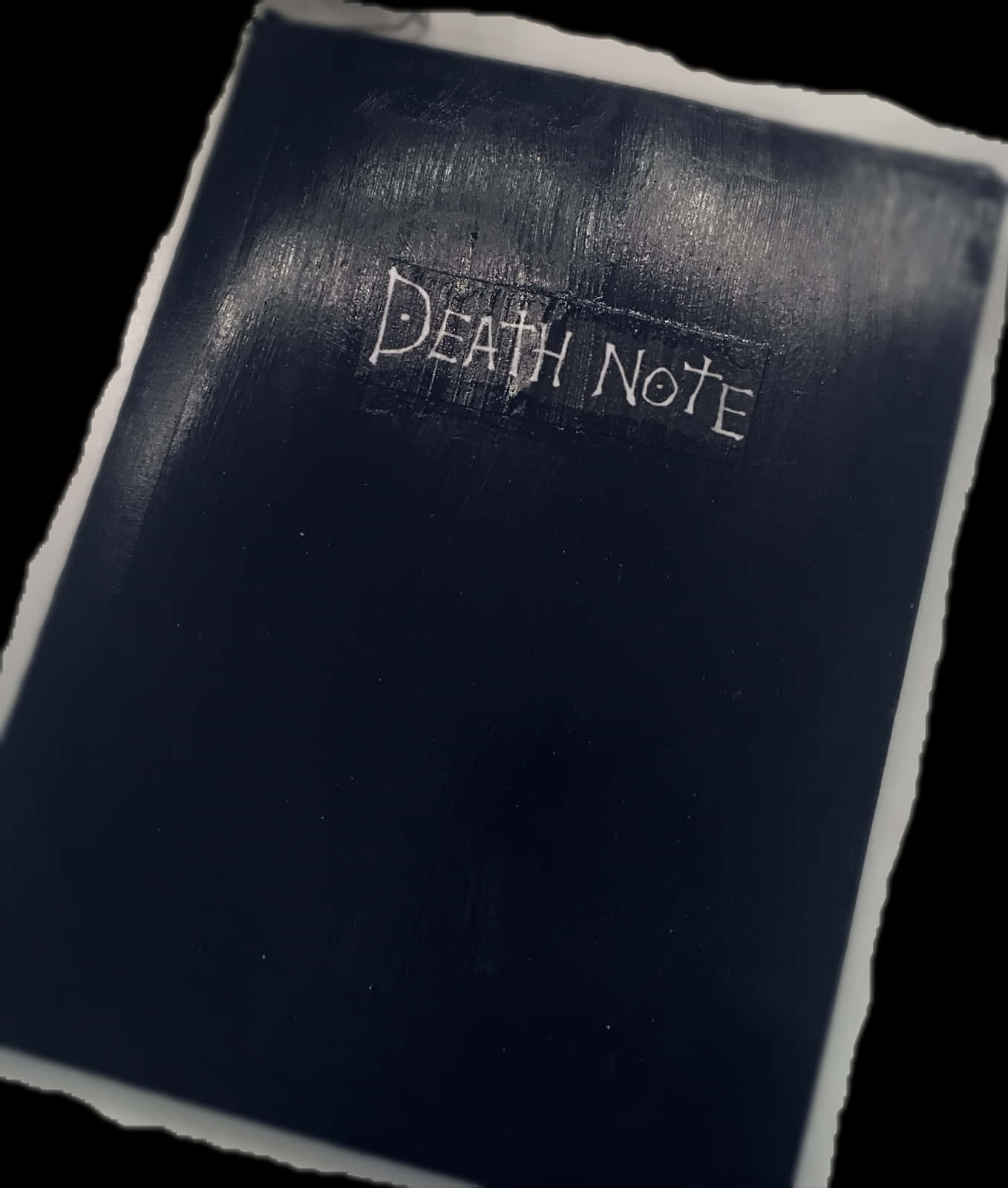 死亡筆記本封面近照 壁紙 — 深藍色死亡筆記本的特寫，帶有白色文字和撕裂的紙張邊緣，背景為黑色。
