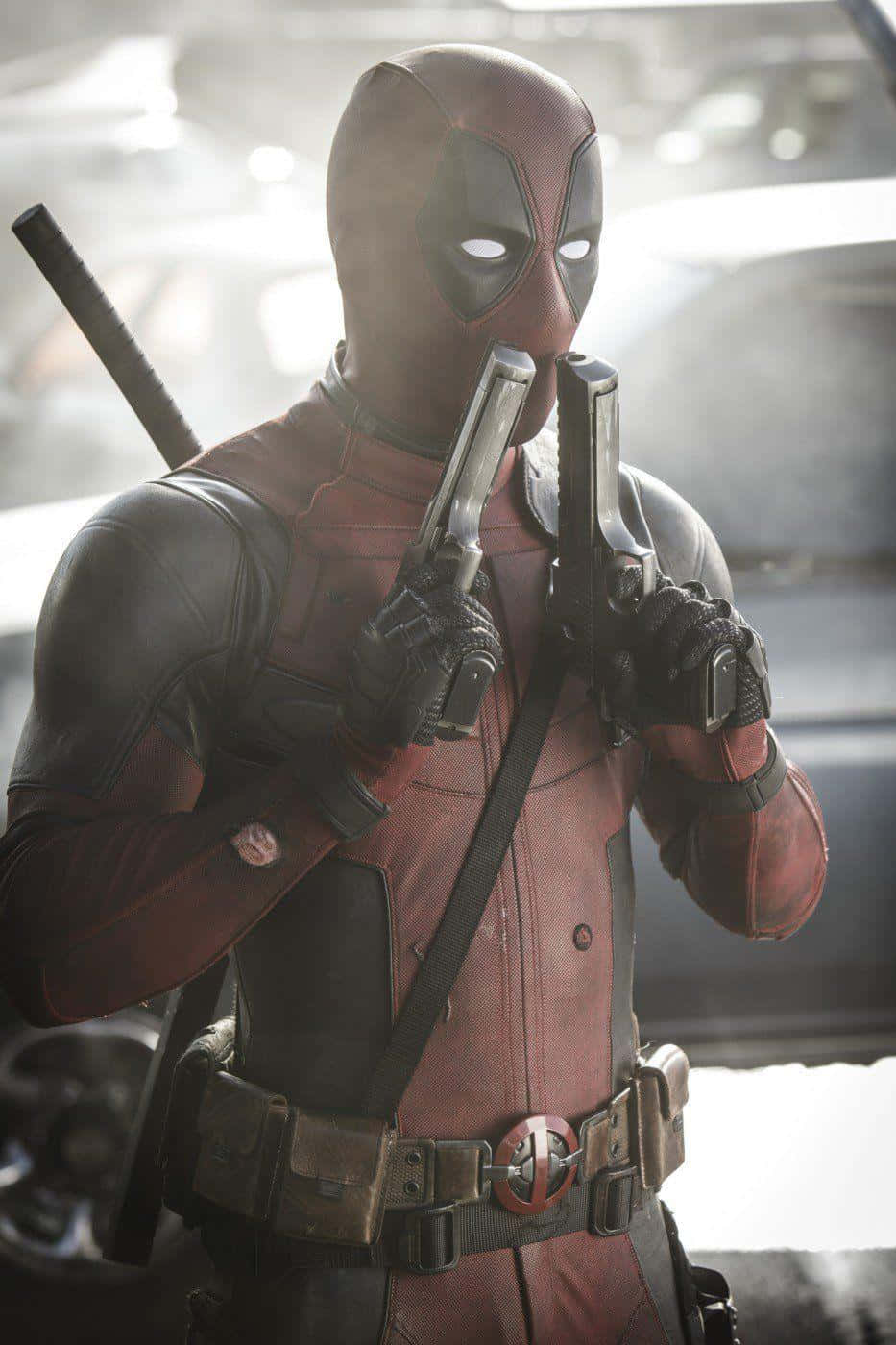 Deadpool 2 桌布 壁紙 — 死侍自信地站立，手持兩把手槍，背上背著一把武士刀，背景是模糊的城市景觀。