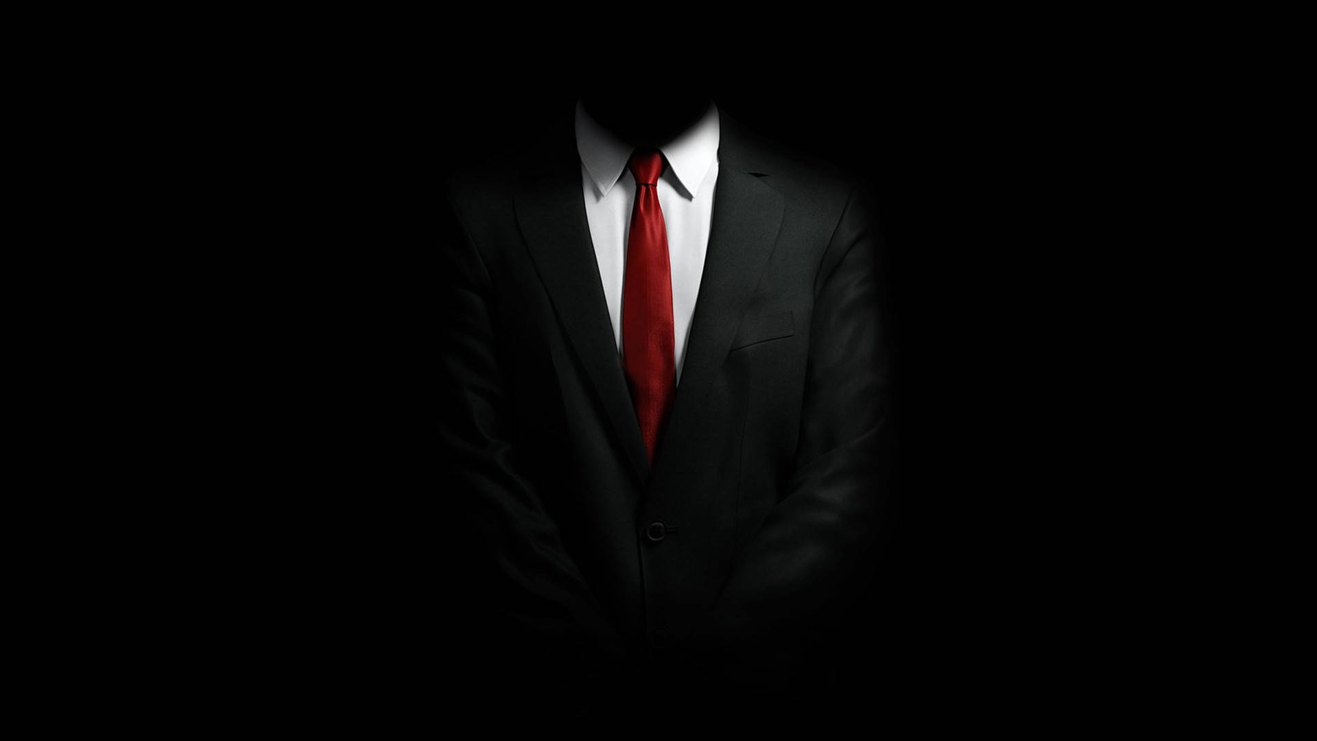 殺手經典西裝 壁紙 — 一個穿著黑色西裝和紅色領帶的男人的剪影站在黑暗中，只有他的軀幹和領帶被照亮。