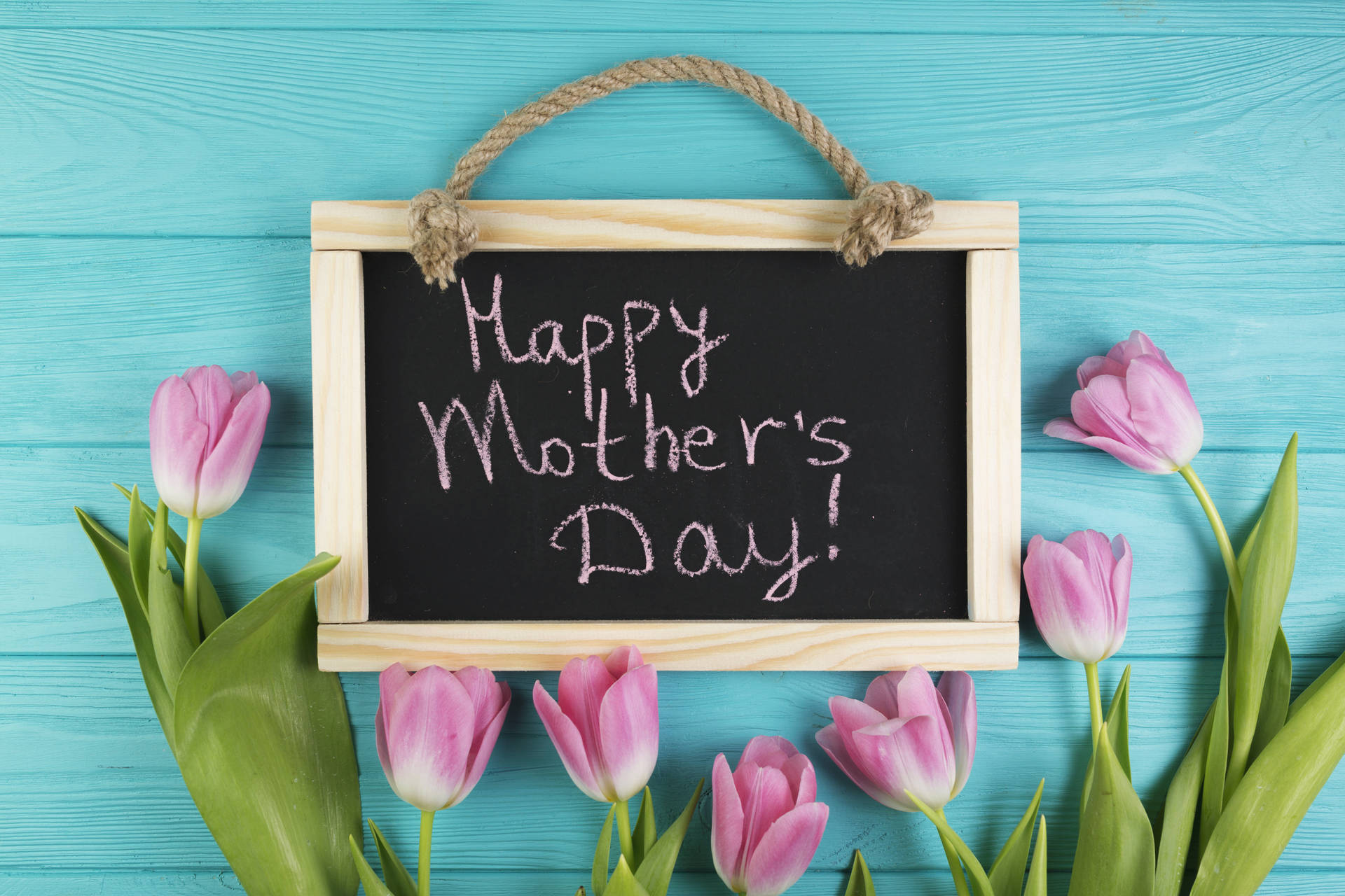 黑板上有Happy Mother's Day訊息，周圍環繞粉紅色鬱金香，背景為藍色木紋。