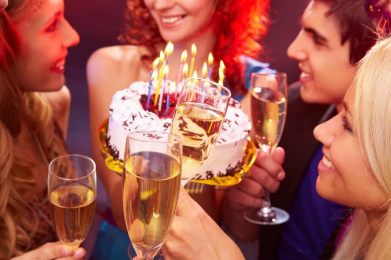 每年慶祝特別的生日！ 壁紙 — 朋友們圍繞著生日蛋糕，點燃蠟燭和香檳杯，進行節日慶祝。