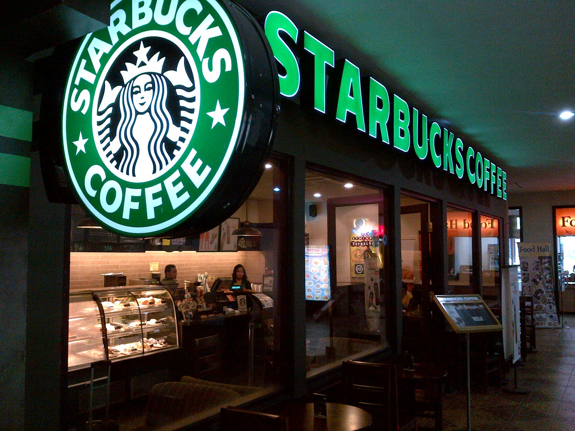 夜晚的Starbucks咖啡店店面，帶有發光的綠色招牌和玻璃窗。