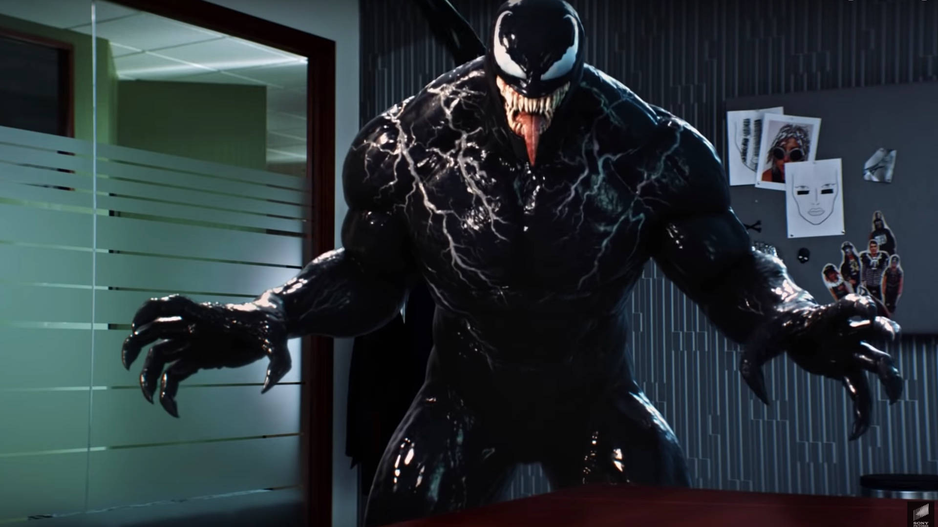 Venom 在一個現代辦公室中，桌上放著文件，牆上掛著海報。