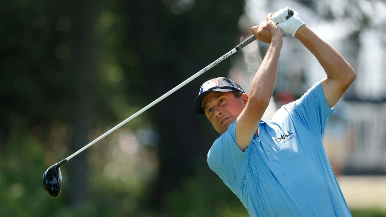 高爾夫球手在陽光明媚的日子裡穿著藍色襯衫和帽子揮桿中